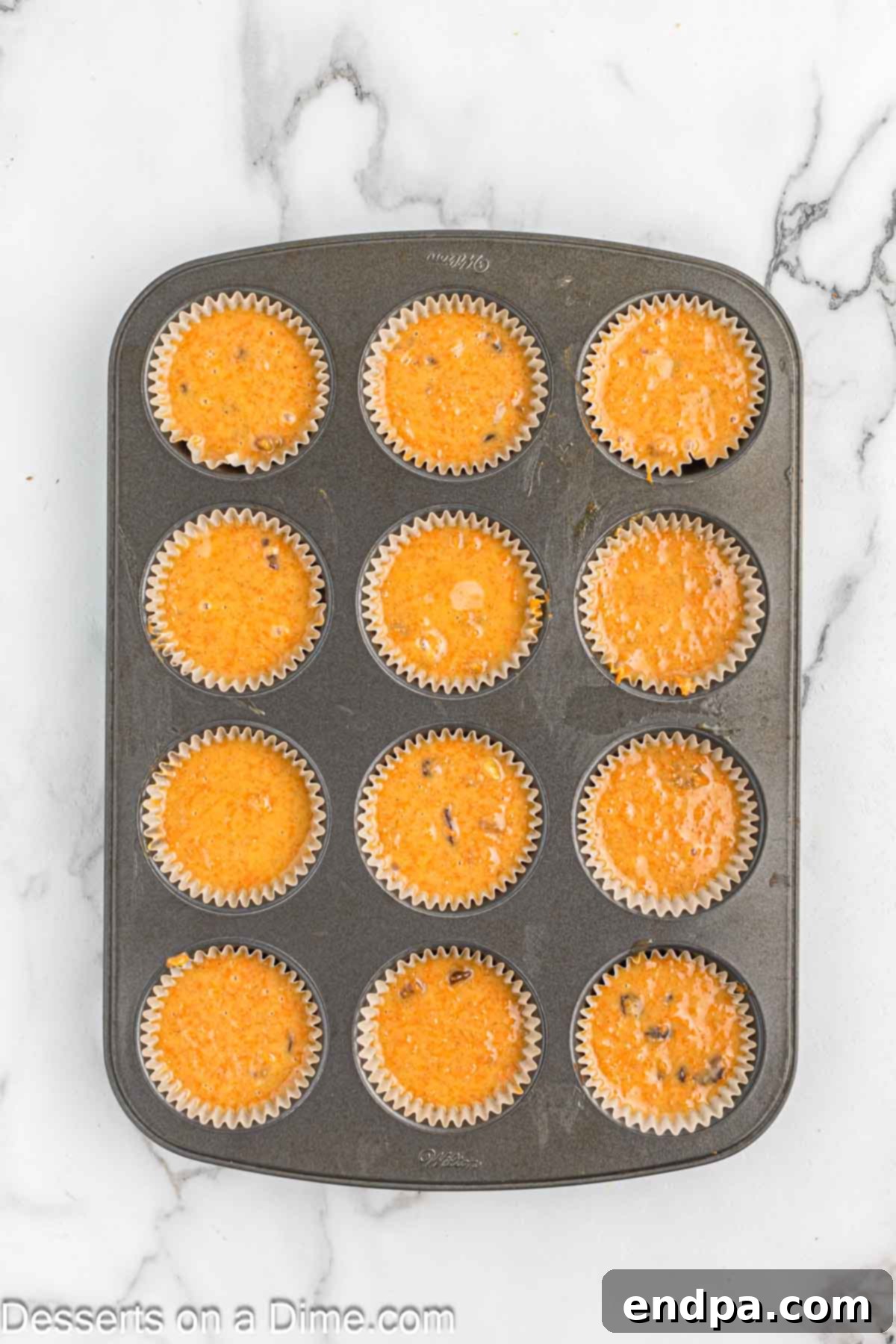 Irresistible Carrot Cake Cupcakes 8 Walnuts and raisins being folded into carrot cake batter with a rubber spatula.