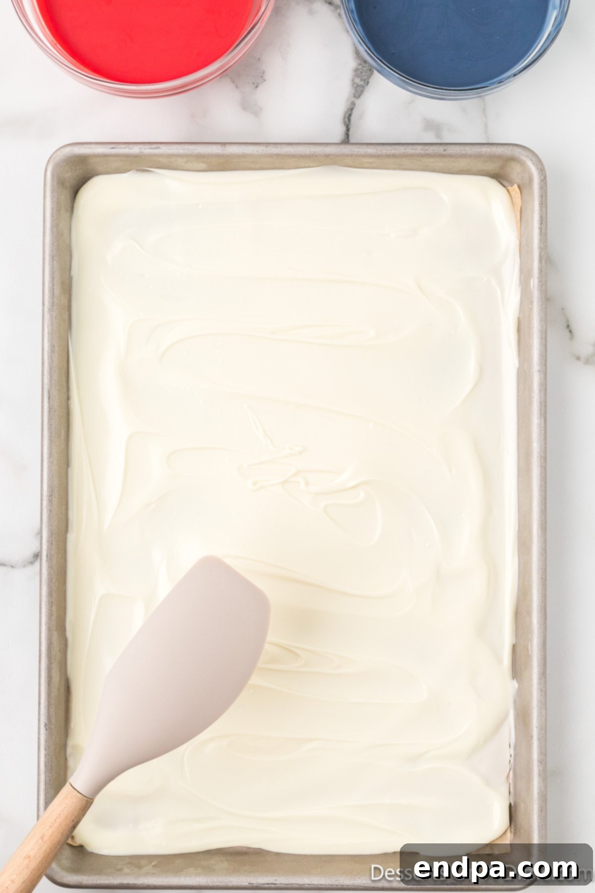 Melted white chocolate spread evenly on a parchment-lined baking sheet.