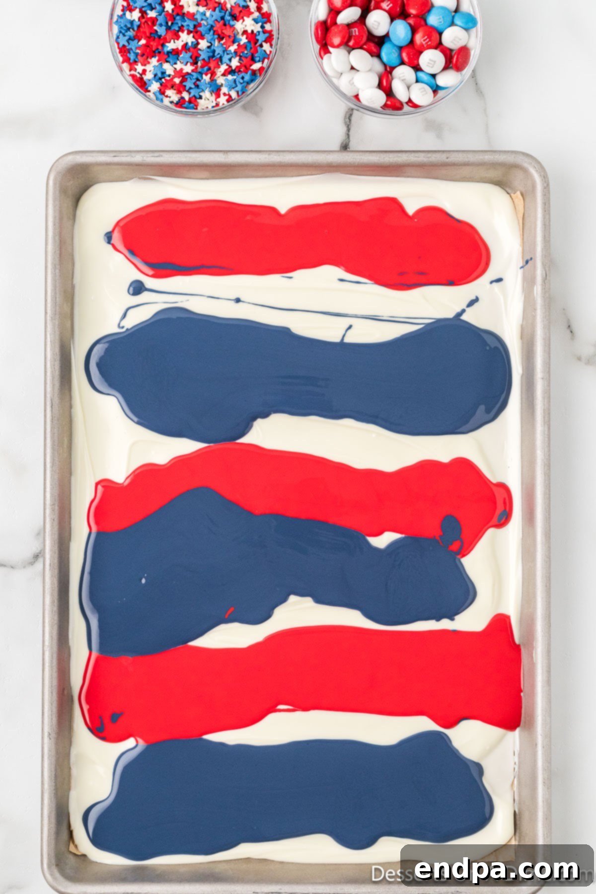 Drizzled red and blue candy melts over the white chocolate base on a baking sheet.