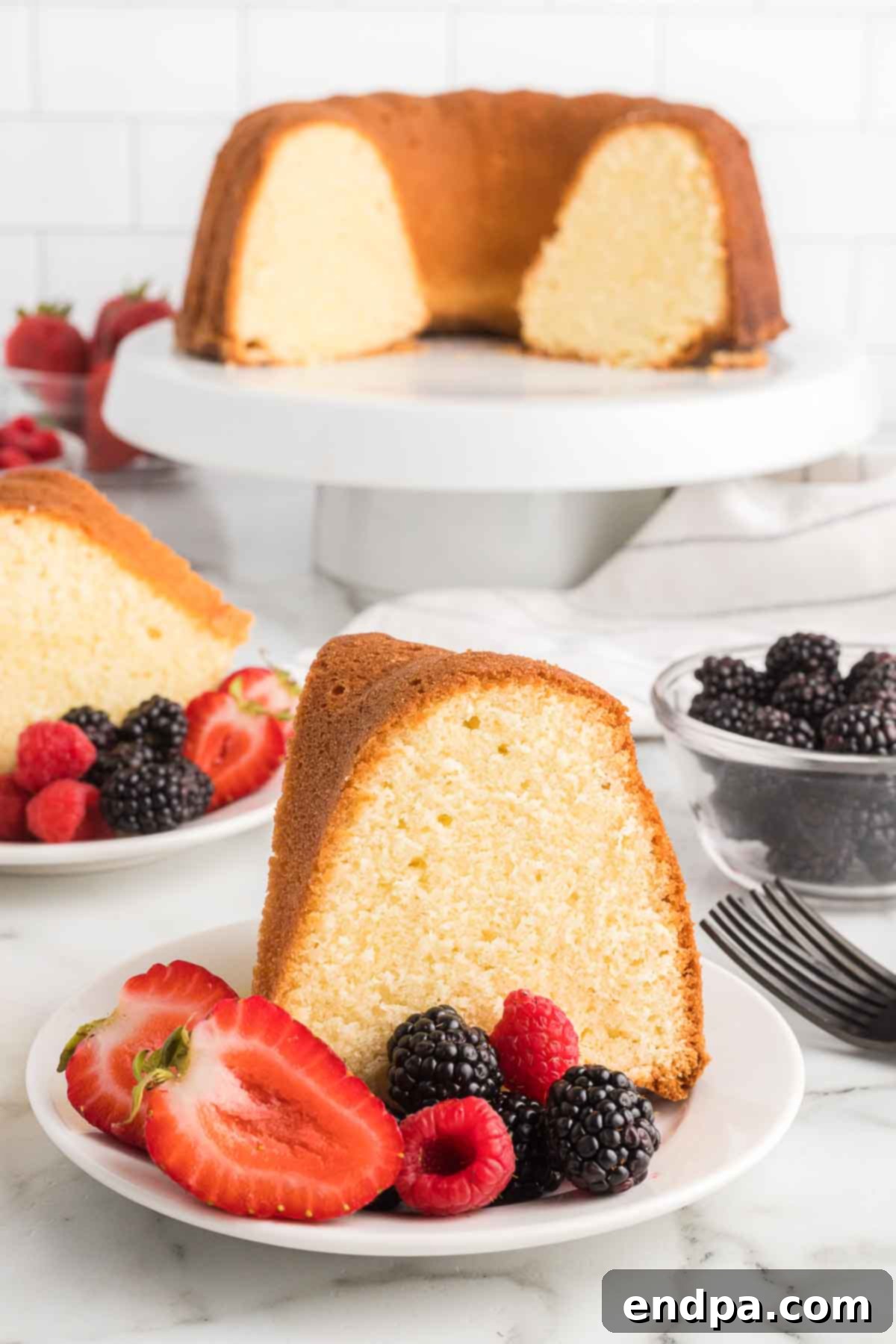 Dreamy Cream Cheese Pound Cake 2 A perfectly sliced cream cheese pound cake, adorned with fresh berries, rests on a plate, showcasing its moist texture and golden-brown crust.