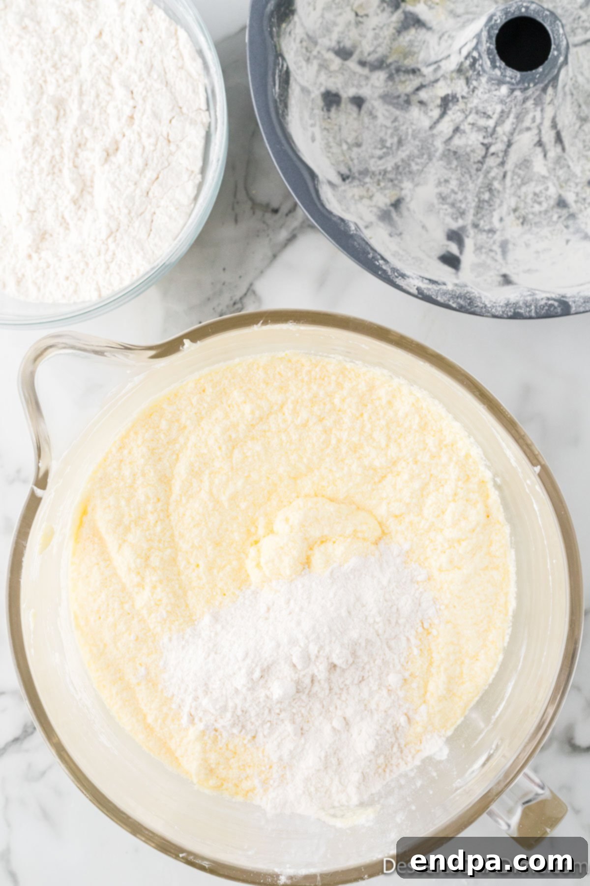 Dreamy Cream Cheese Pound Cake 11 All-purpose flour is gradually added to the wet ingredients in the mixing bowl, signaling the final stage of preparing the pound cake batter.
