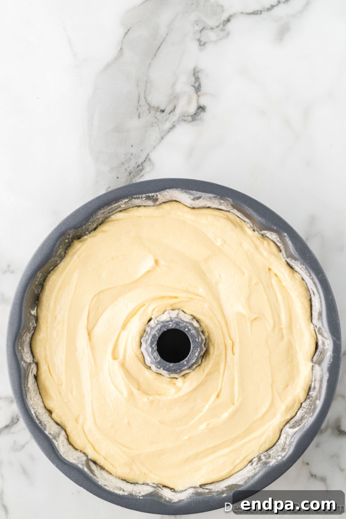 Dreamy Cream Cheese Pound Cake 13 The smooth pound cake batter is meticulously spread into a prepared bundt pan, filling it evenly and preparing it for baking.