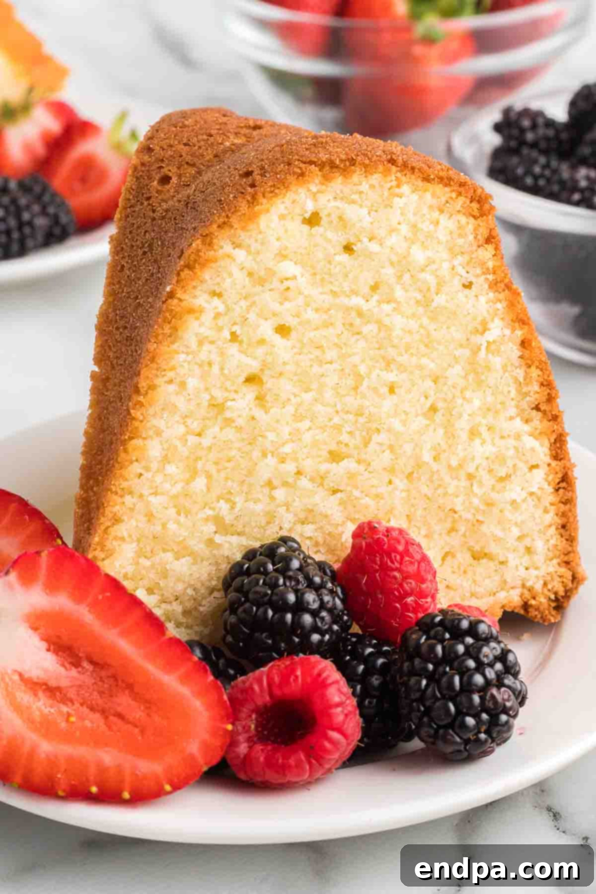 Dreamy Cream Cheese Pound Cake 16 A slice of cream cheese pound cake, elegantly presented on a plate with an assortment of fresh berries, creating a visually appealing and delicious dessert.