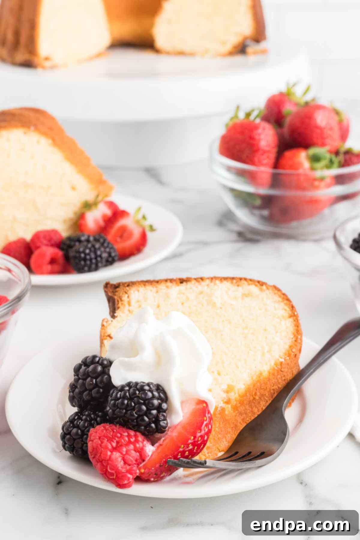 Dreamy Cream Cheese Pound Cake 17 A beautiful slice of cream cheese pound cake garnished with a generous serving of fresh mixed berries, highlighting the cake's inviting texture and vibrant toppings.