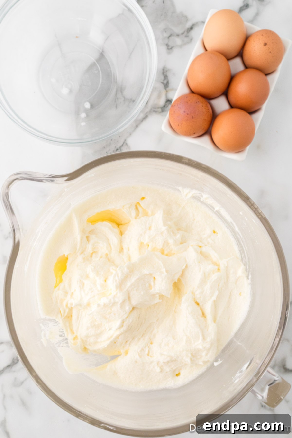 Dreamy Cream Cheese Pound Cake 8 Fresh eggs are cracked and added one by one into the creamy sugar and butter mixture, ensuring proper integration into the pound cake batter.