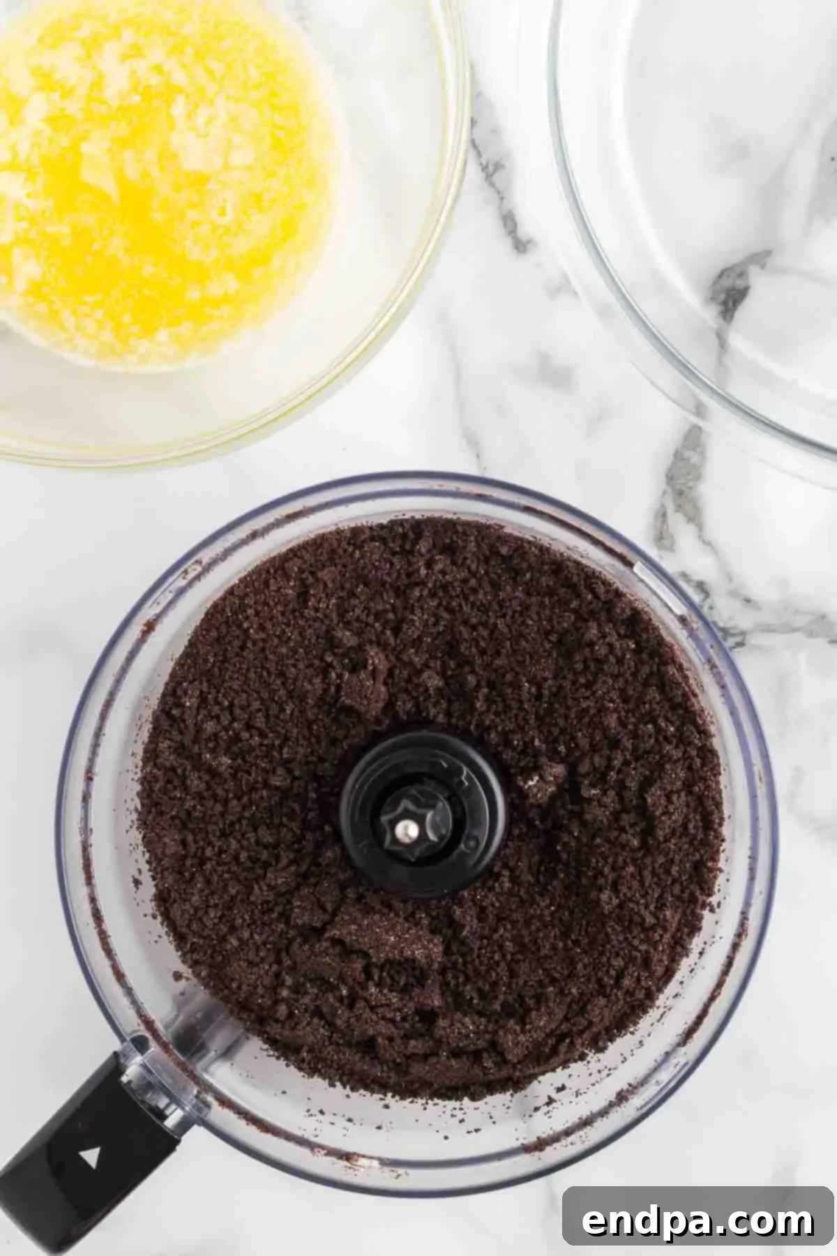 Oreo cookies being crushed into fine crumbs in a food processor.