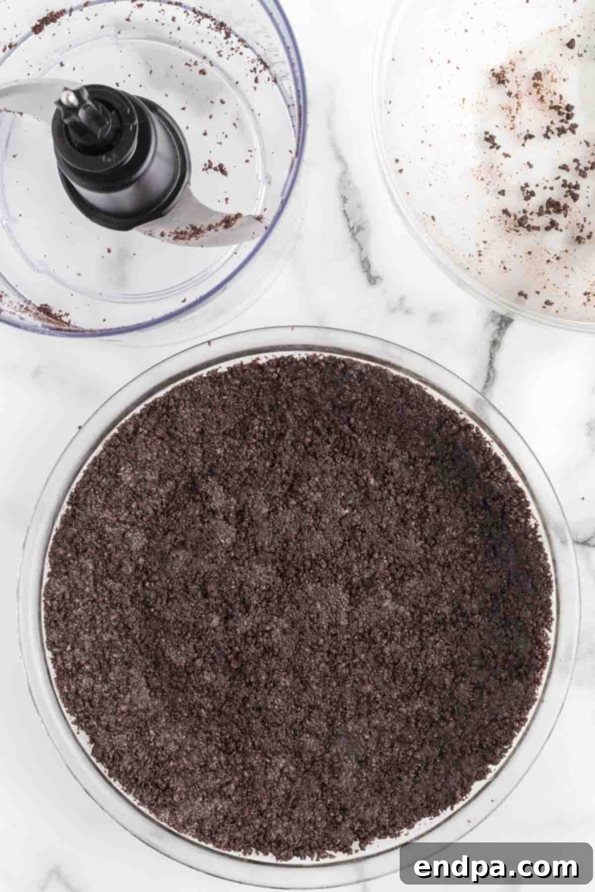 Oreo cookie crumbs pressed firmly into a pie plate, forming the crust.