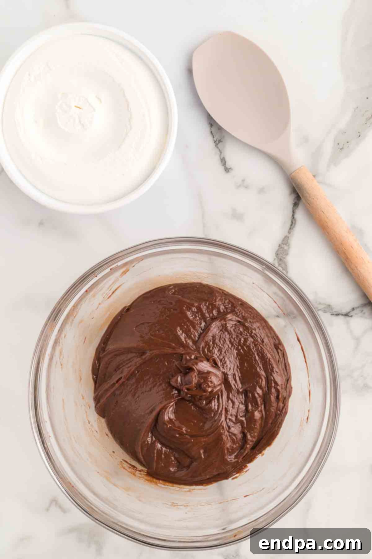 Nutella hazelnut spread being mixed into the fluffy cream cheese.