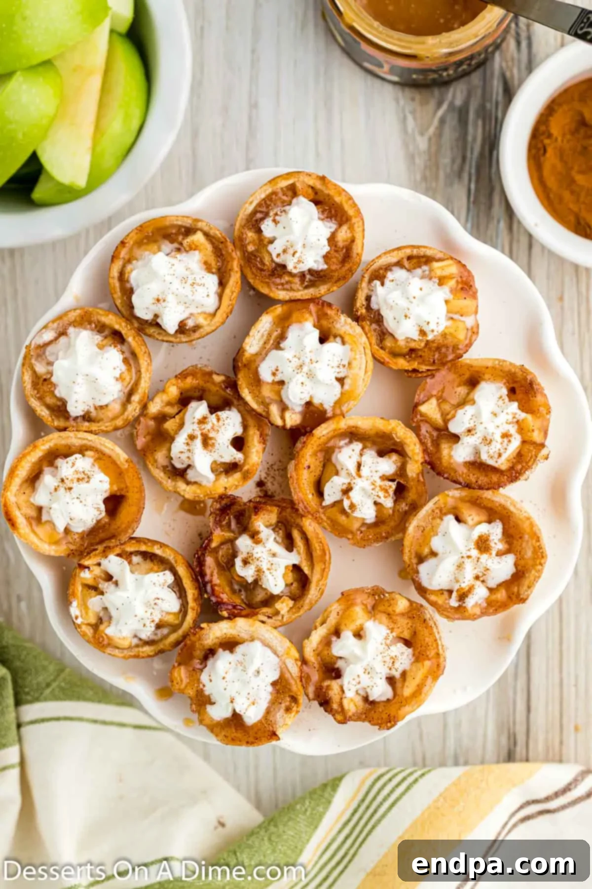 A serving platter adorned with Mini Apple Pie Bites, generously topped with whipped cream and a drizzle of caramel.