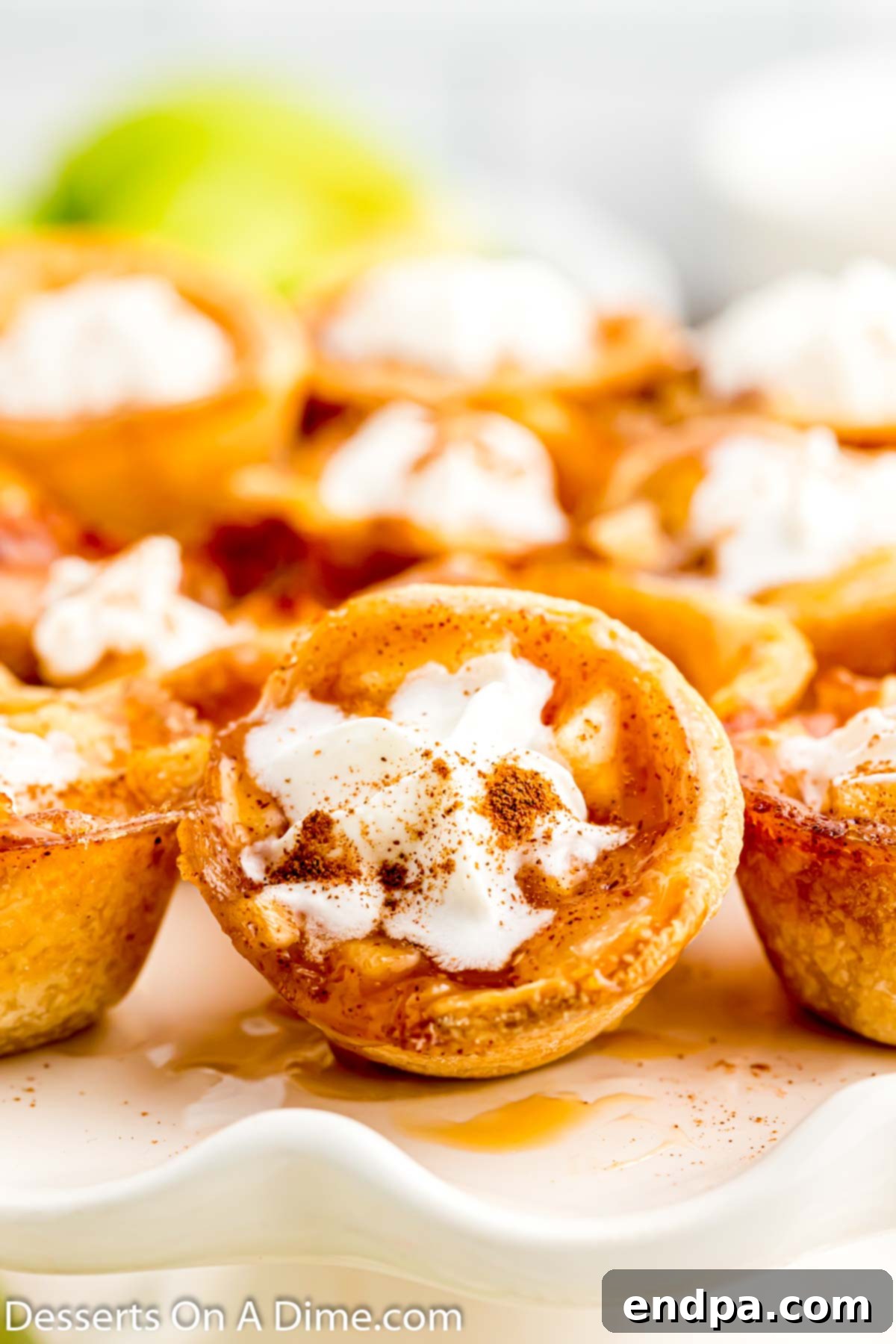 A close-up view of golden-brown Mini Apple Pie Bites on a rustic wooden platter, ready to be served.