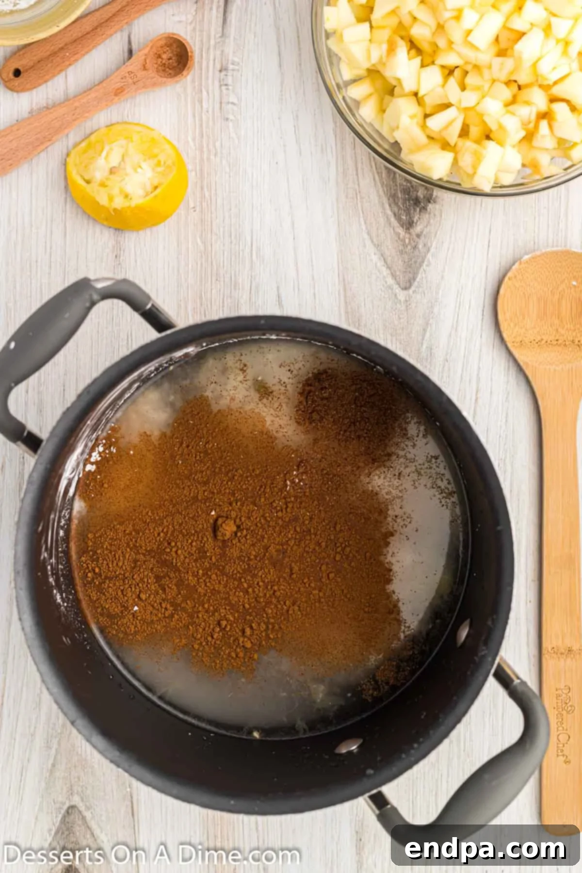 A saucepan filled with a simmering mixture of water, sugar, and spices for the apple pie filling.