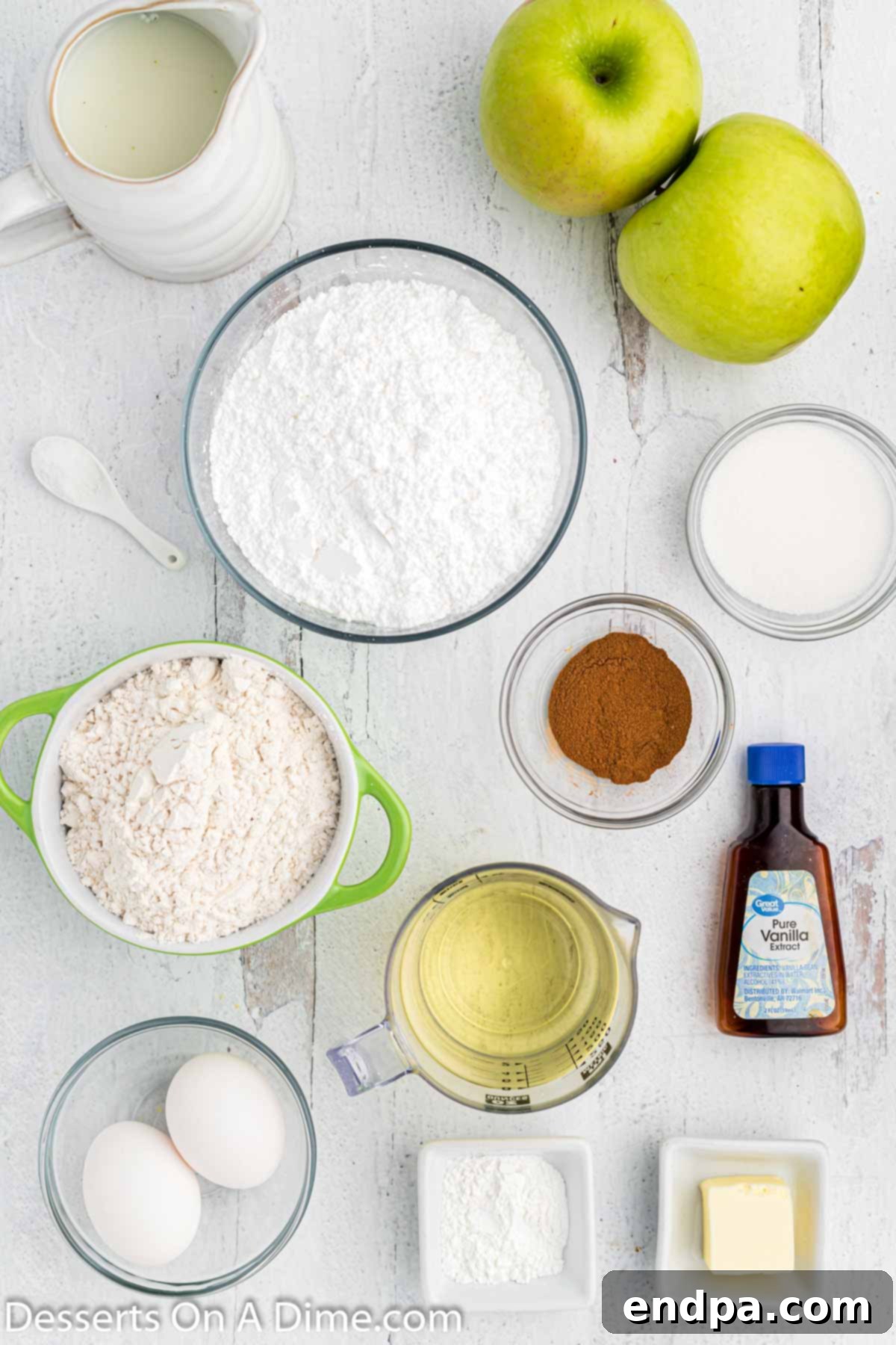 Golden Crisp Apple Fritters 3 A beautiful flat lay of all the essential ingredients for making apple fritters: flour, cinnamon, milk, melted butter, vanilla extract, Granny Smith apples, vegetable oil, and powdered sugar, neatly arranged on a rustic wooden surface.