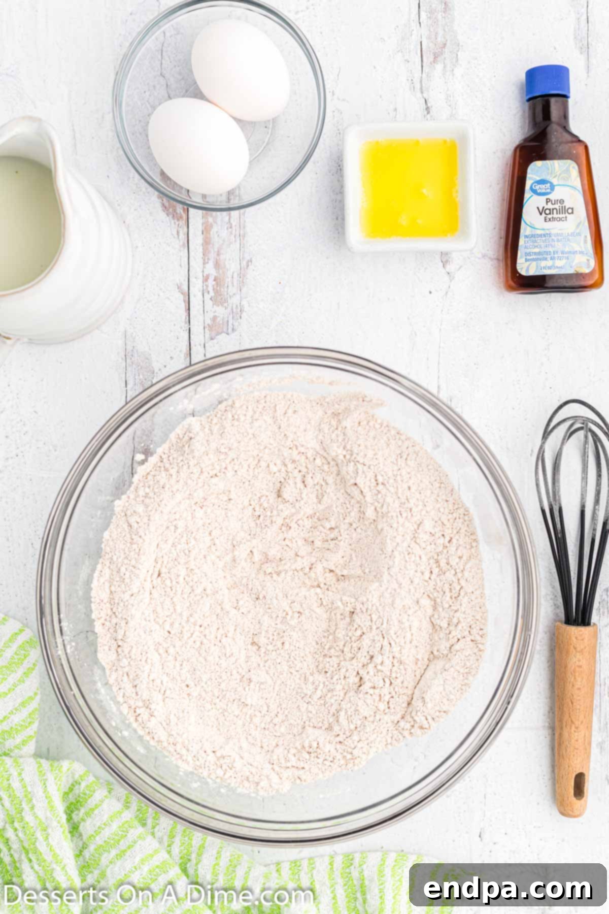 Golden Crisp Apple Fritters 4 A mixing bowl filled with dry ingredients for apple fritters, including flour, sugar, baking powder, salt, and cinnamon, perfectly combined and ready for the wet ingredients.