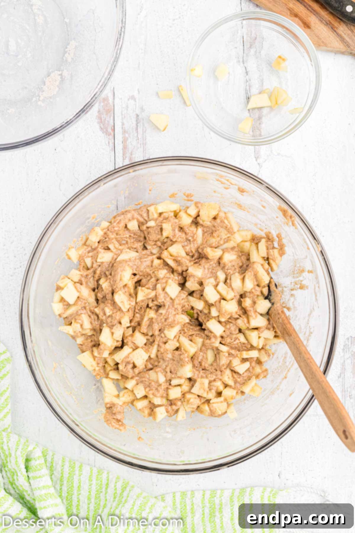 Golden Crisp Apple Fritters 6 A large mixing bowl containing the apple fritter batter, where the wet and dry ingredients have been combined, and the diced apple chunks are carefully folded in, creating a lumpy, rustic mixture.