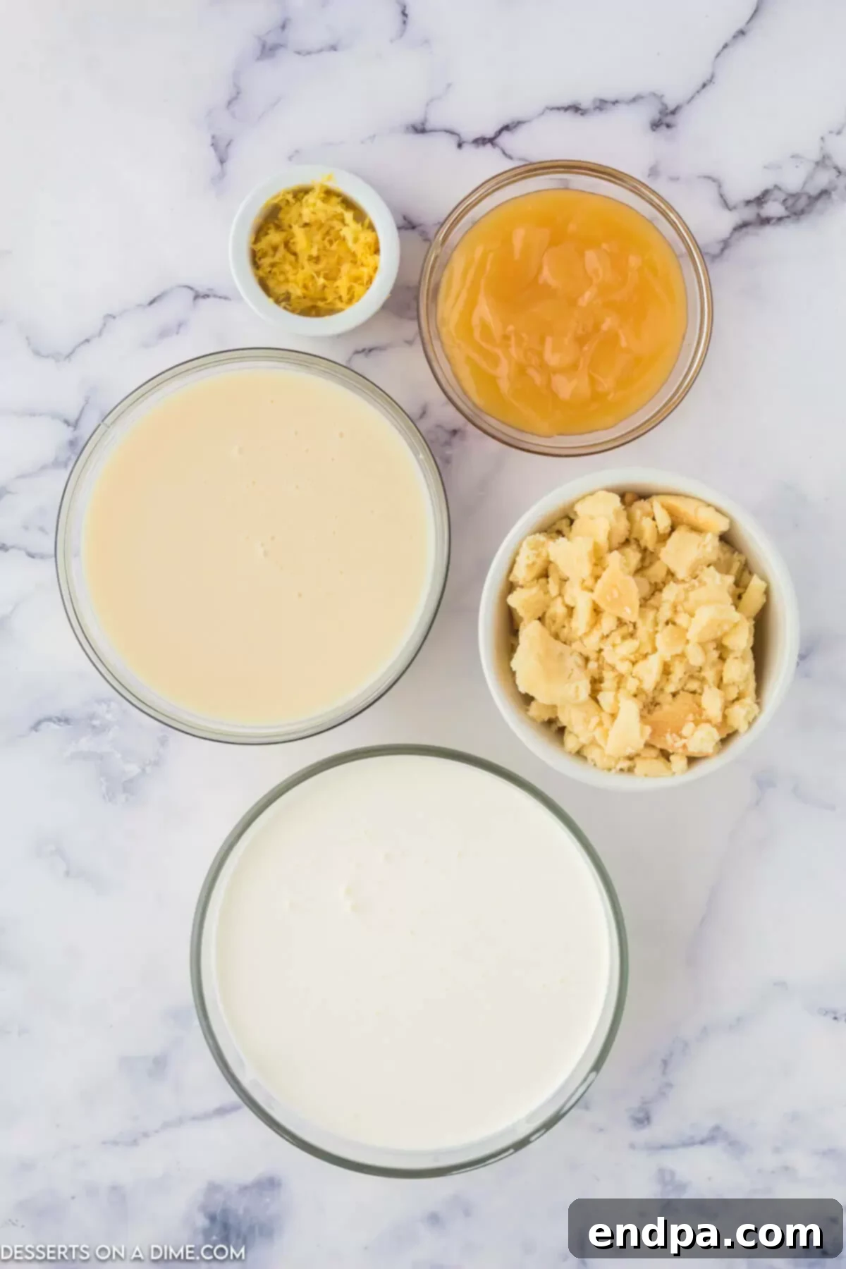 Zesty Shortbread Crumble Ice Cream 3 A flat lay image of ingredients for Lemon Shortbread Ice Cream, including heavy cream, sweetened condensed milk, lemon curd, shortbread cookies, and fresh lemons.