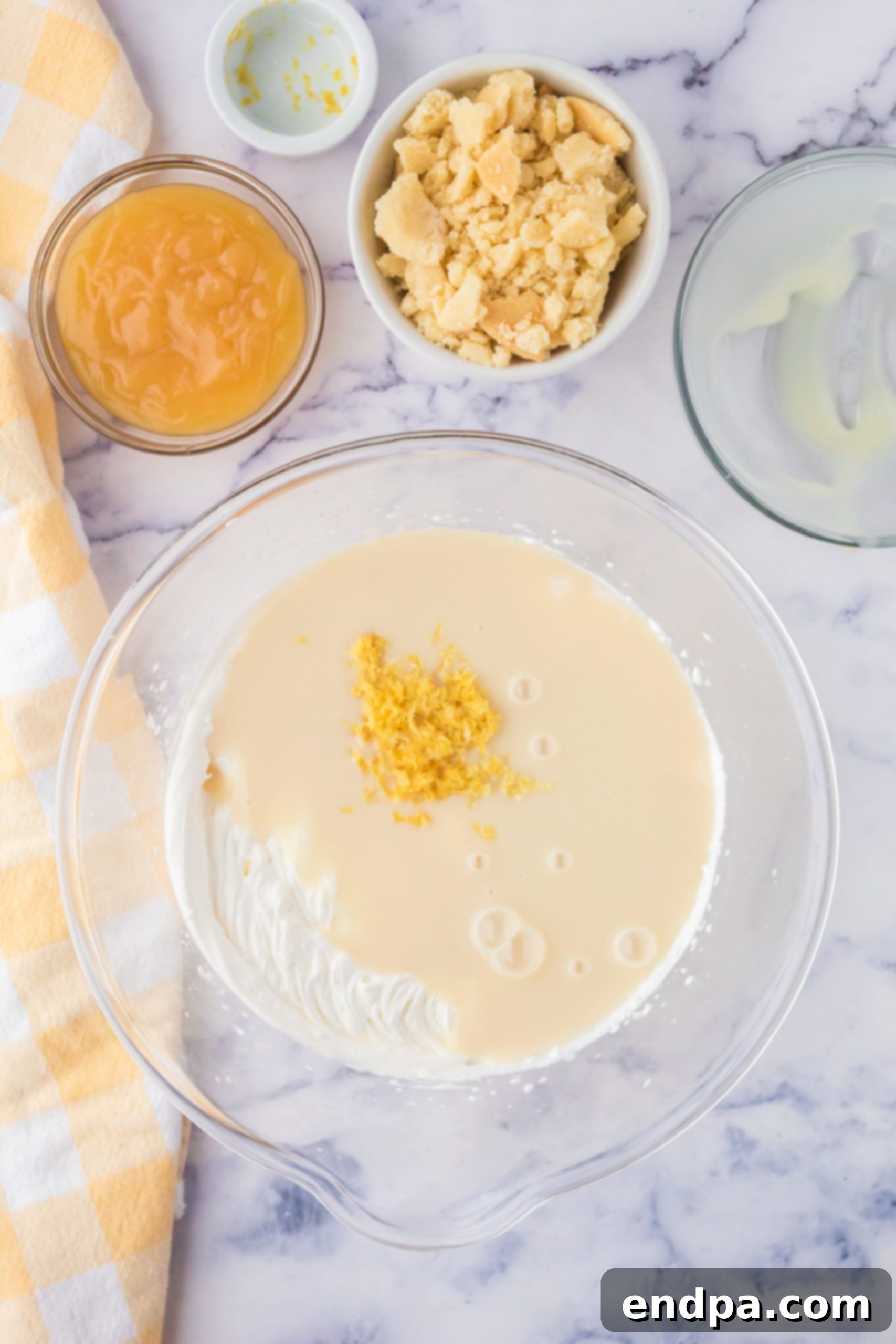 Zesty Shortbread Crumble Ice Cream 4 Mixing bowl with sweetened condensed milk and lemon zest being combined with whipped cream.