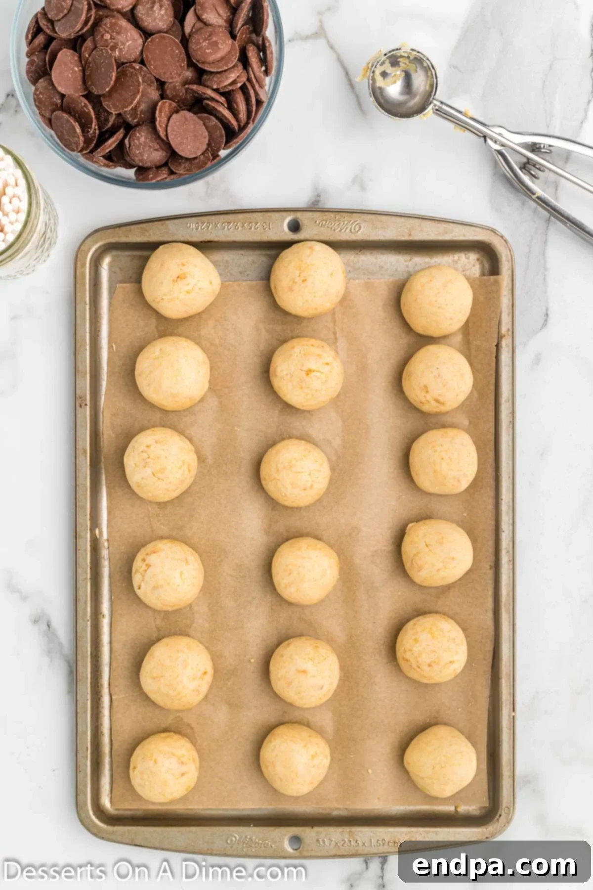Uniform cake balls arranged neatly on a baking sheet lined with parchment paper, ready for freezing.