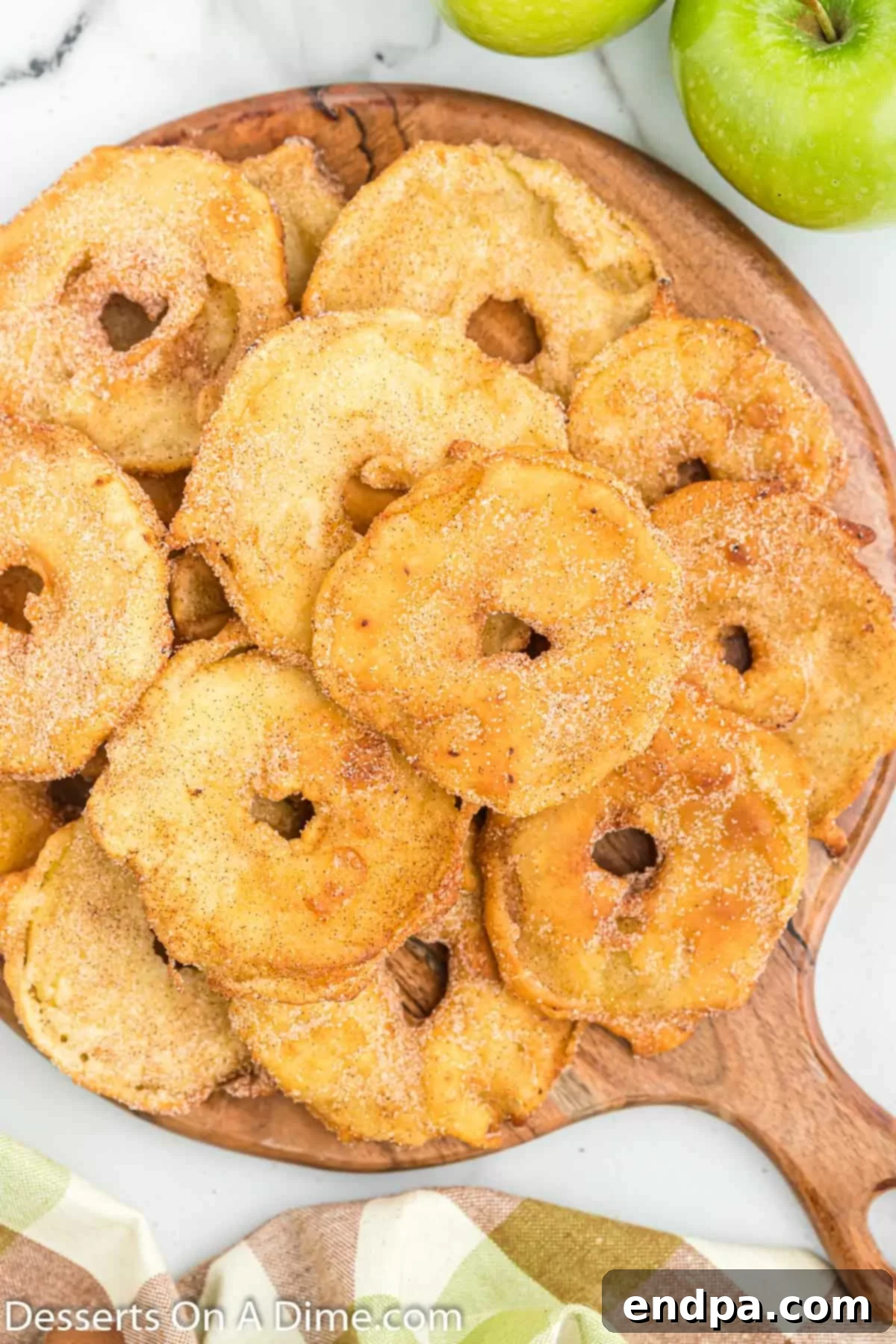 Beautifully fried apple slices stacked on a rustic brown platter, glistening with cinnamon sugar.