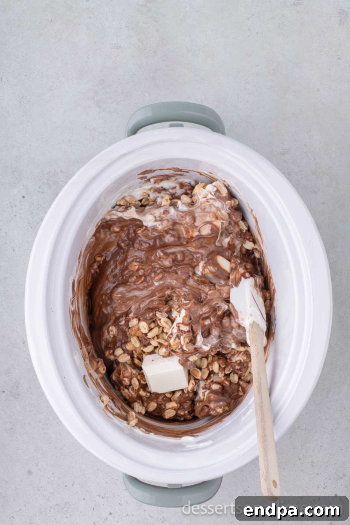 Mixture being combined with a spatula as it melts in a crock pot.