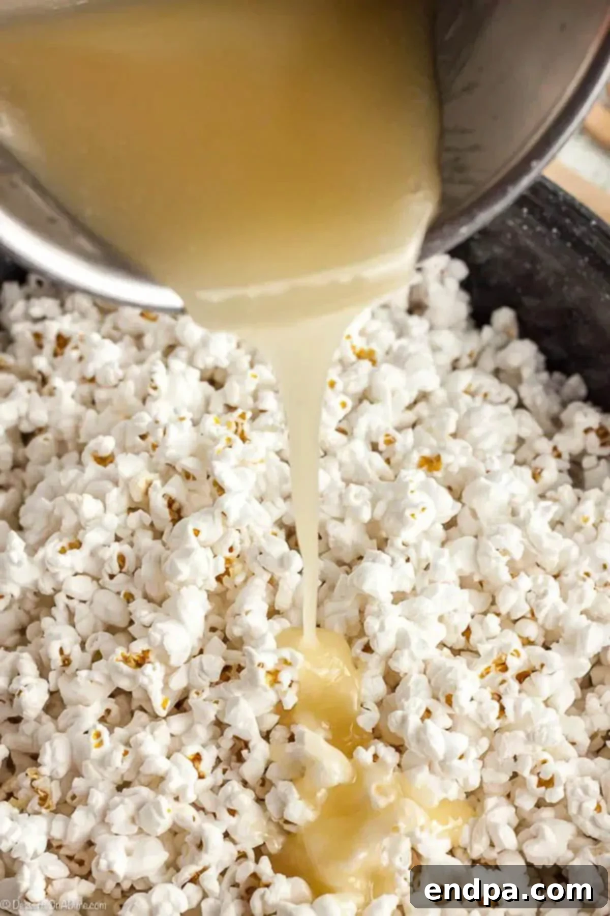 The corn syrup mixture being poured over the popped popcorn