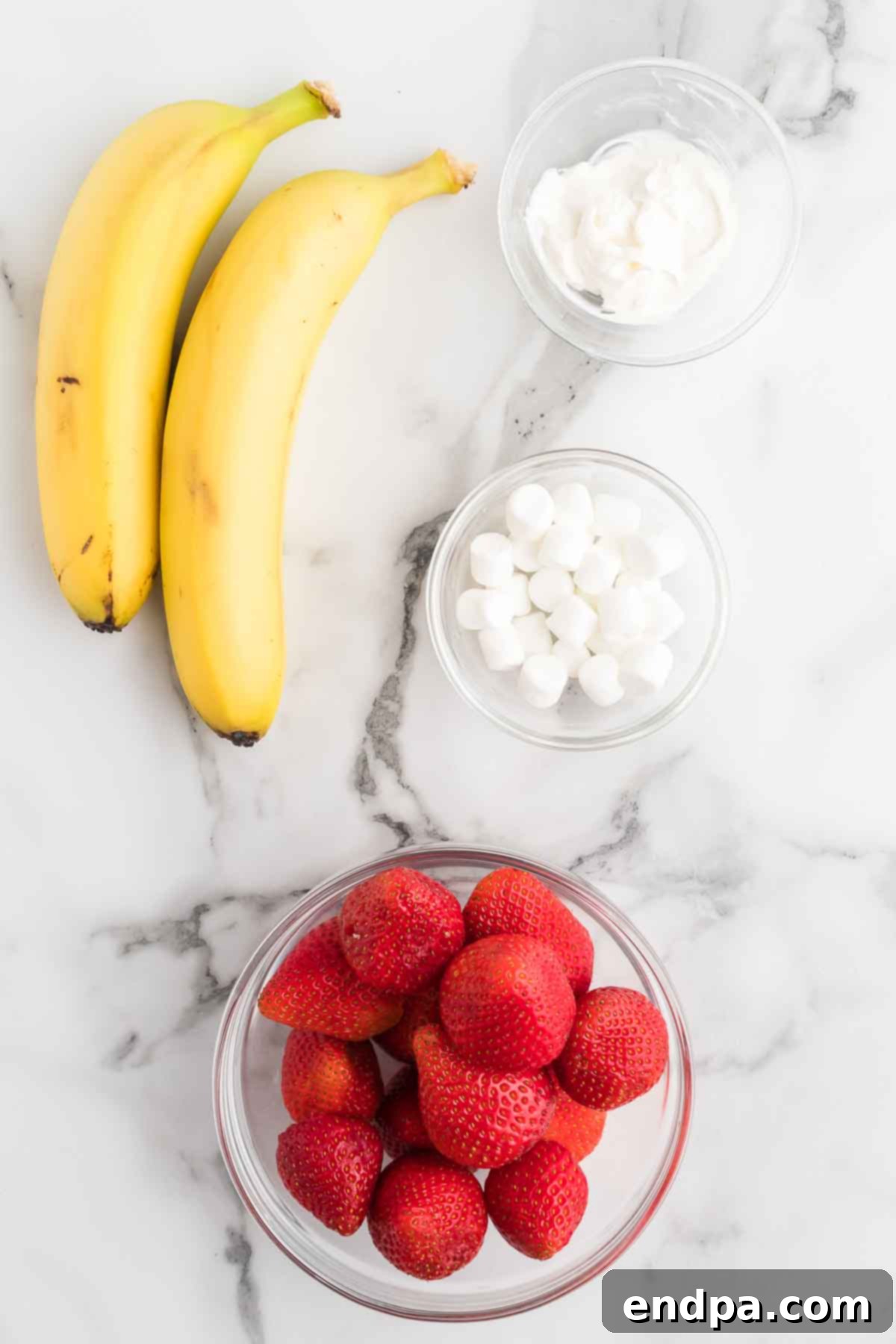 Ingredients for Santa hats - fresh strawberries, ripe bananas, mini marshmallows, and melted white chocolate.