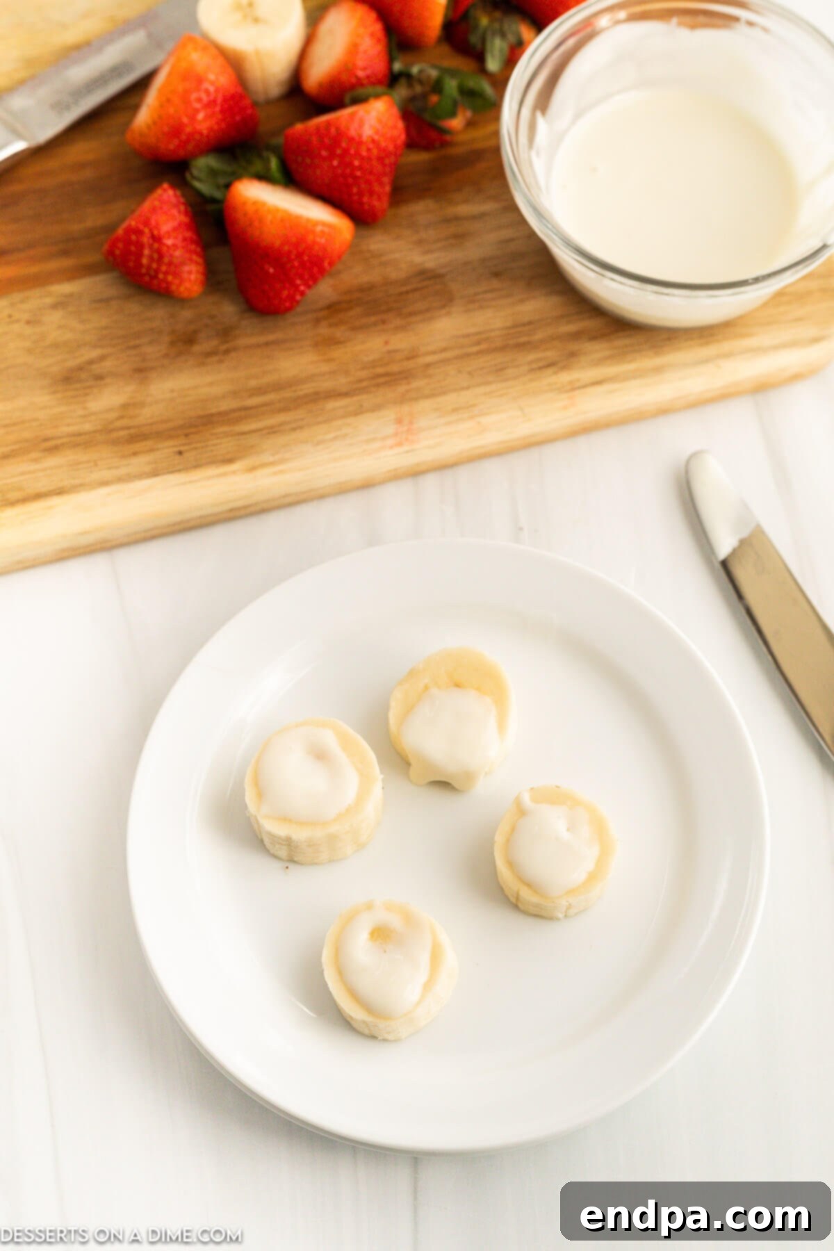 Melted white chocolate spread thinly on top of banana slices.
