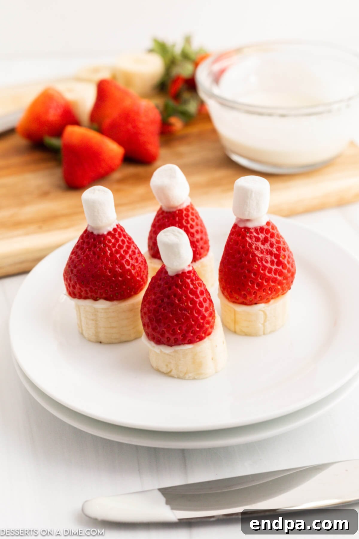 Mini marshmallows dipped in chocolate and placed on top of each strawberry.