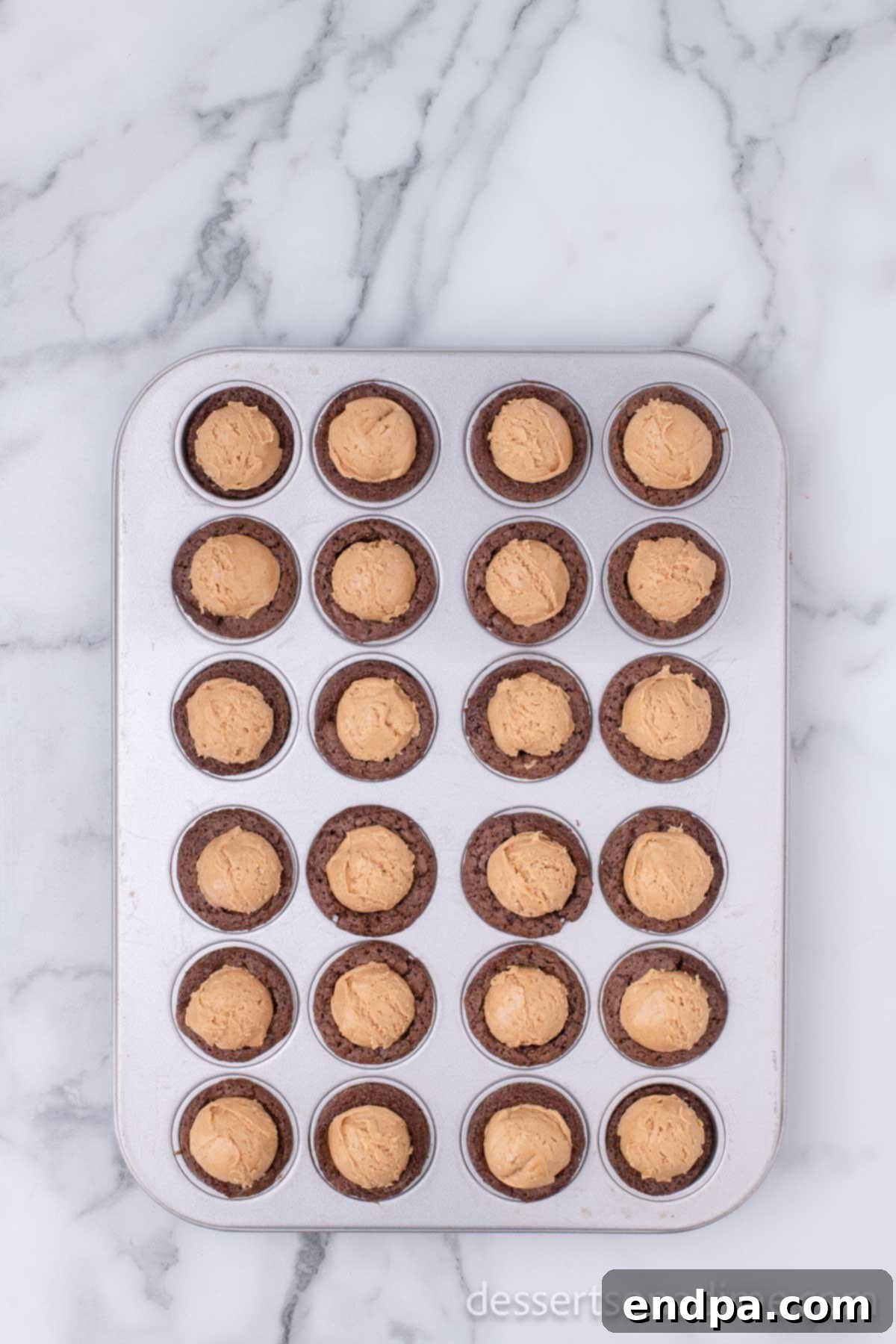 Peanut Butter Brownie Bliss Bites 9 Warm brownie bites in a muffin tin with peanut butter balls pressed into each one.