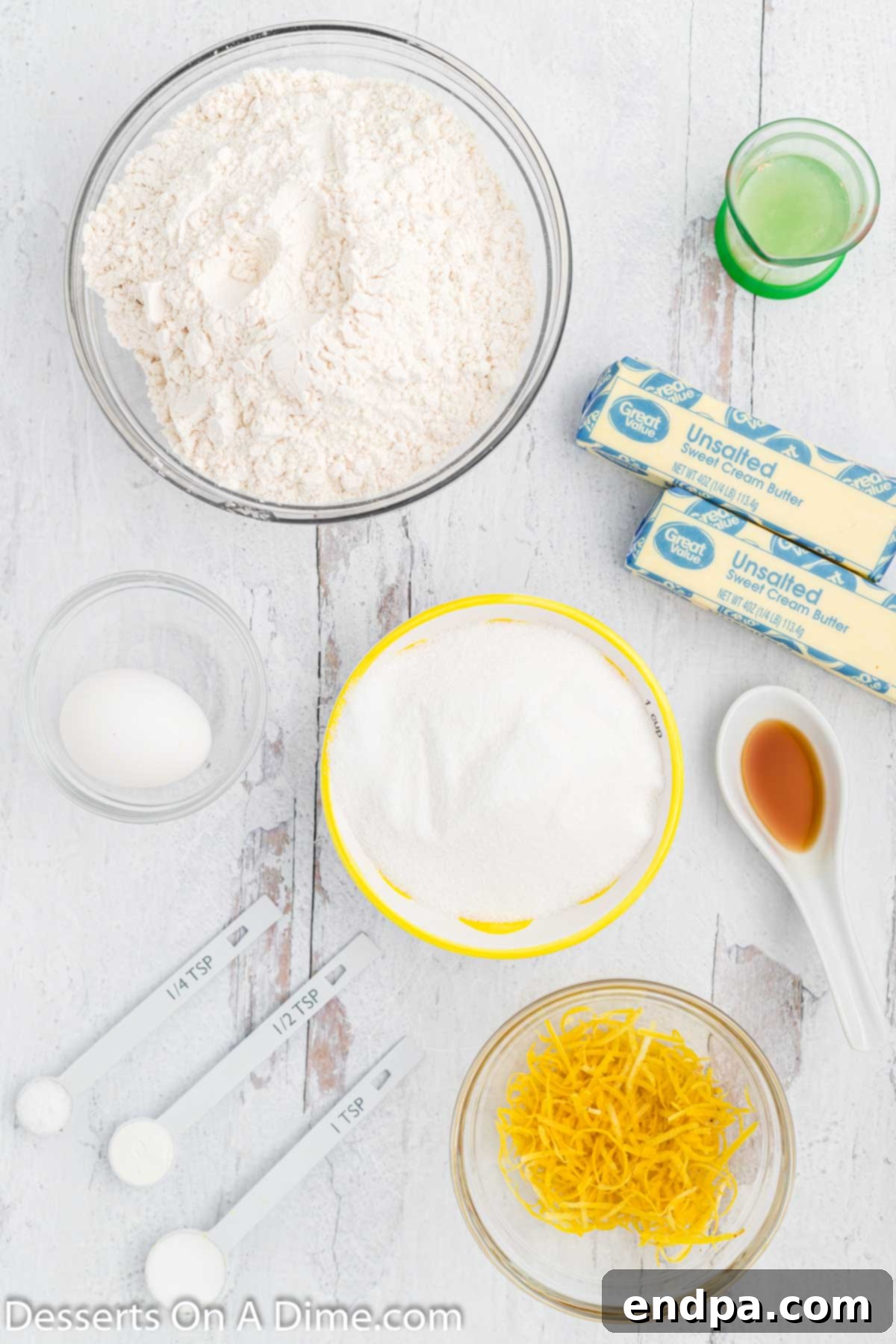 Ingredients for Lemon sugar cookies - flour, baking soda, butter, lemons, lemon juice, egg, vanilla, sugar on a rustic wooden surface.