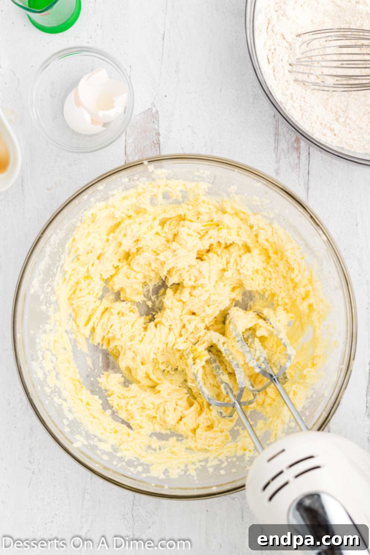 Fresh lemon juice, a large egg, and vanilla extract being mixed into the creamed butter and sugar mixture.