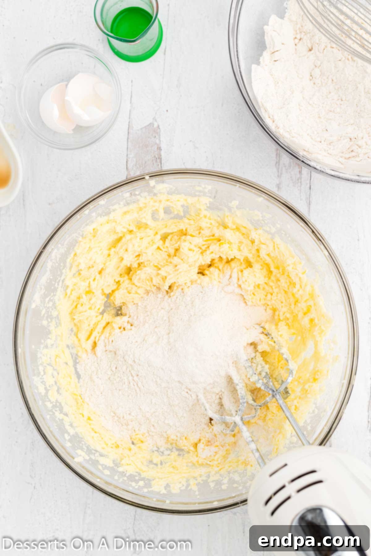 Gradually mixing the dry ingredients into the wet ingredients in a large mixing bowl to form the cookie dough.