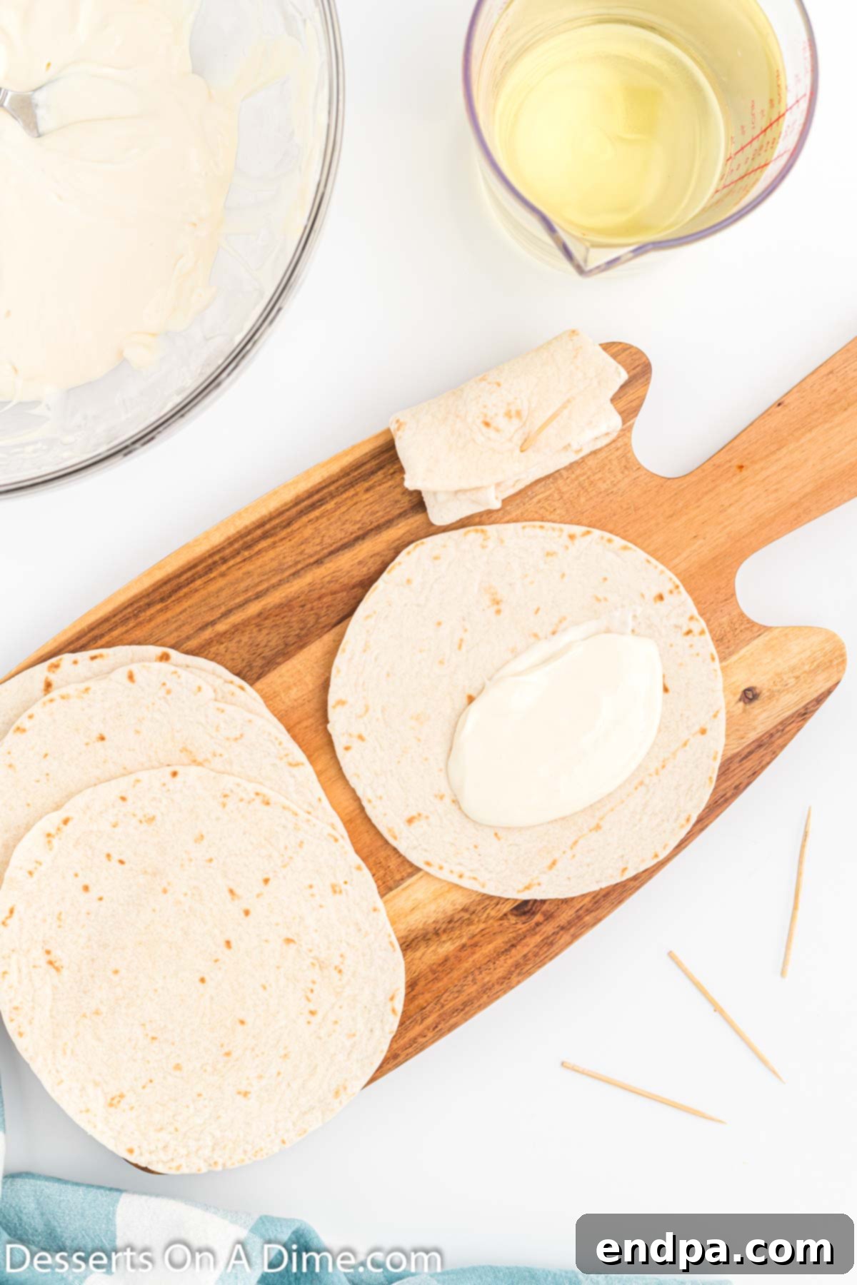 Crispy Cheesecake Chimis 6 Cheesecake mixture being added to the bottom half of each tortilla, ready for rolling.