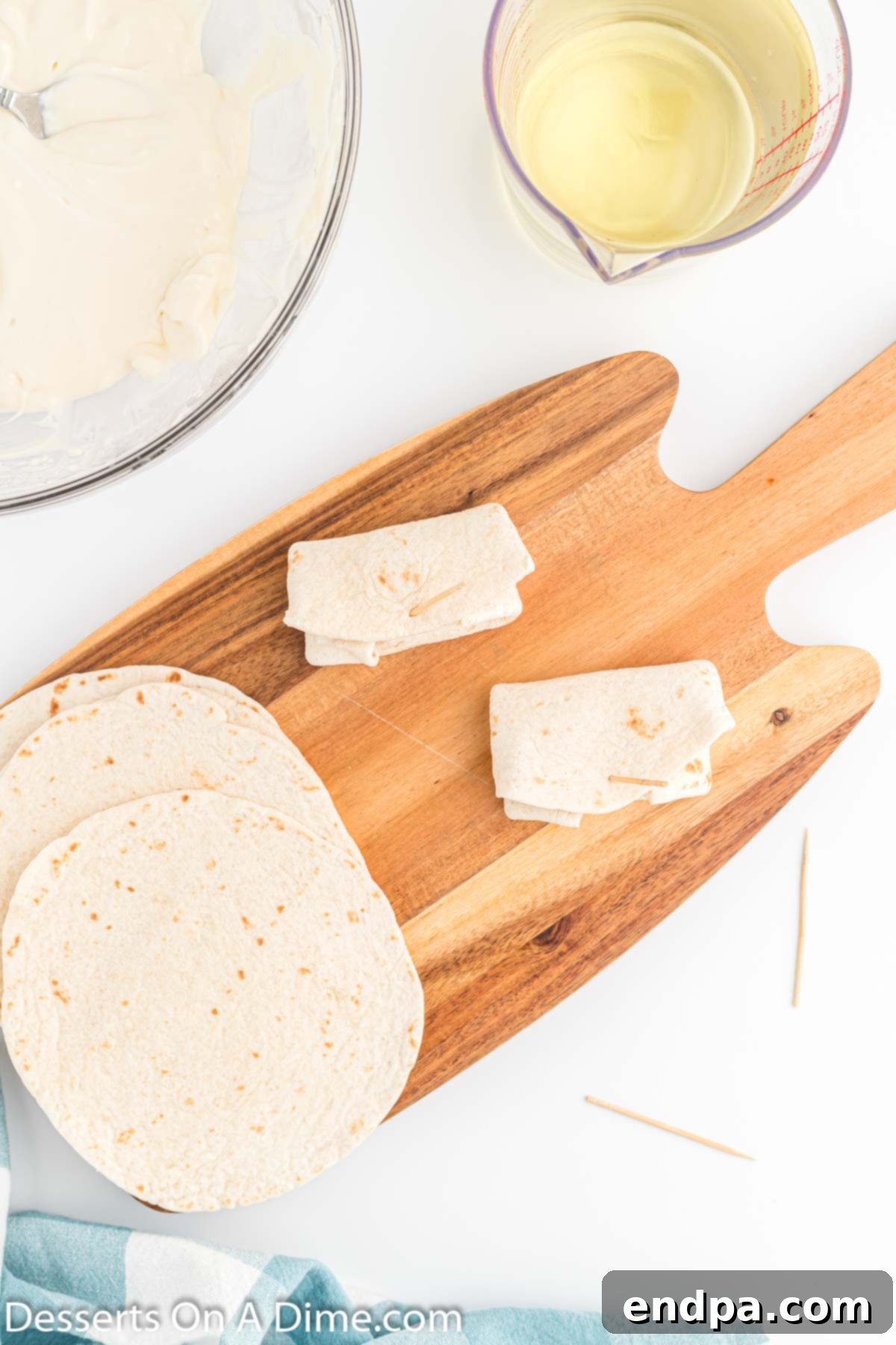 Crispy Cheesecake Chimis 7 A rolled-up chimichanga with sides tucked in, secured with a toothpick before frying.