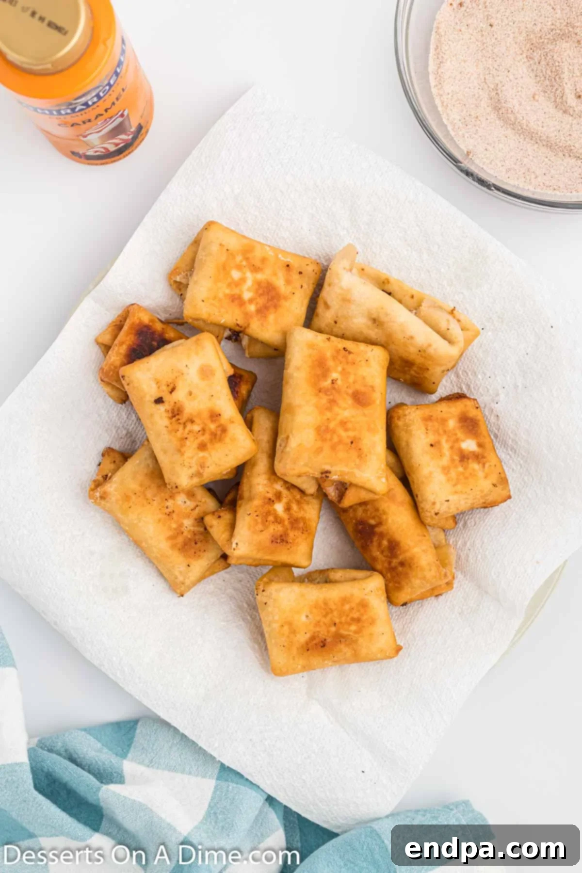 Crispy Cheesecake Chimis 8 Freshly fried chimichangas draining on a paper towel-lined plate to remove excess oil.