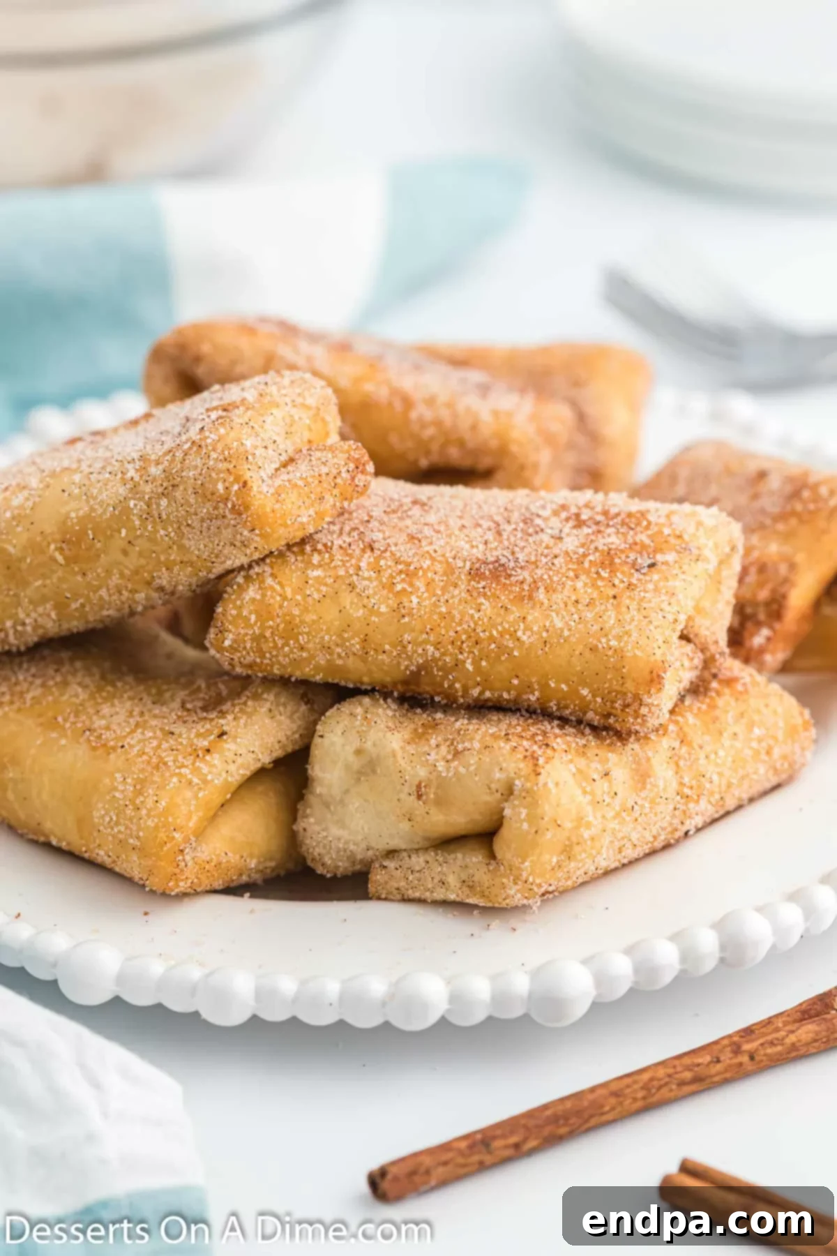 Crispy Cheesecake Chimis 9 Hot chimichangas being rolled in a bowl of cinnamon sugar mixture for a sweet coating.