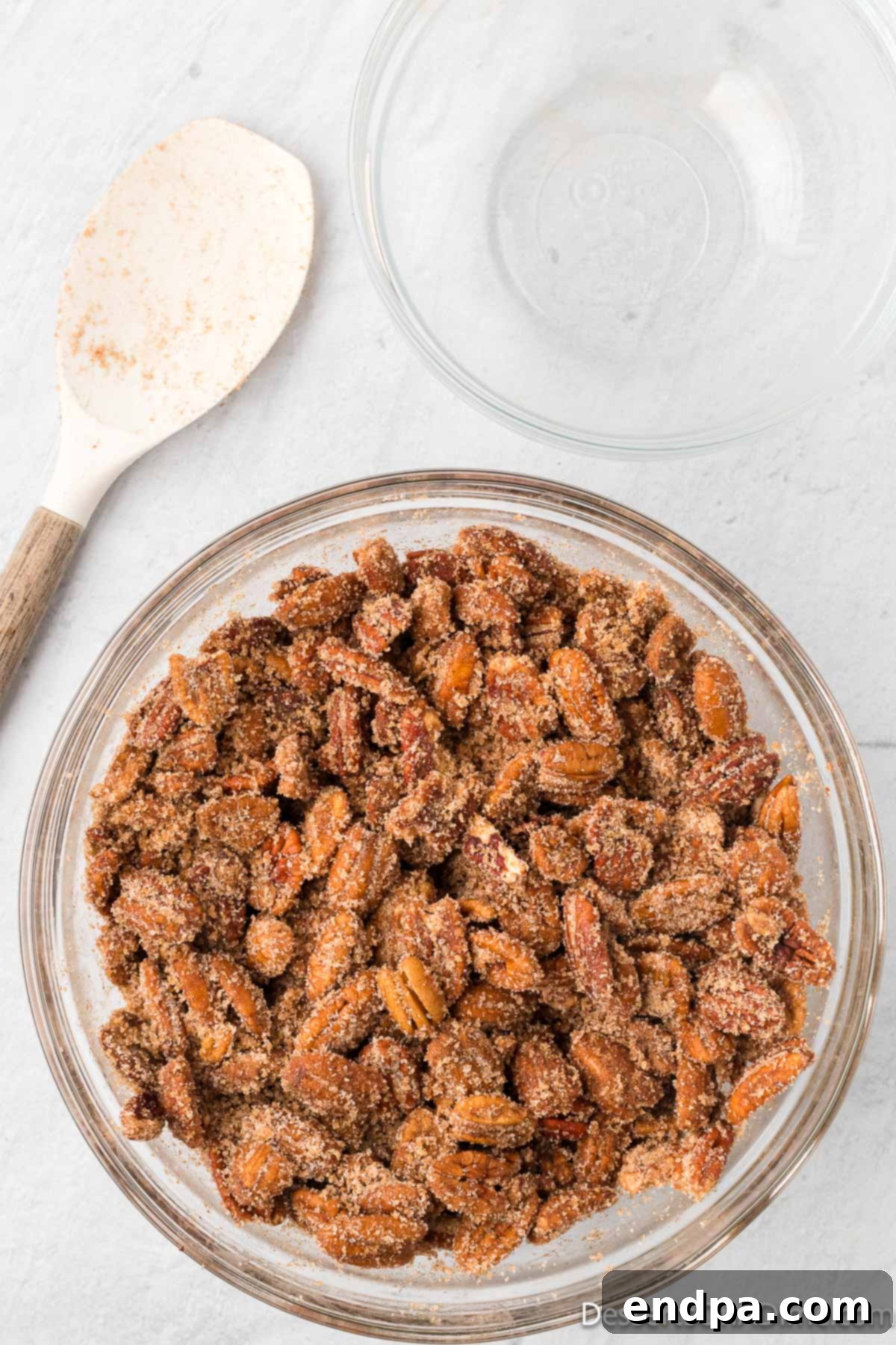 Cinnamon mixture combined together with pecans in a bowl. 