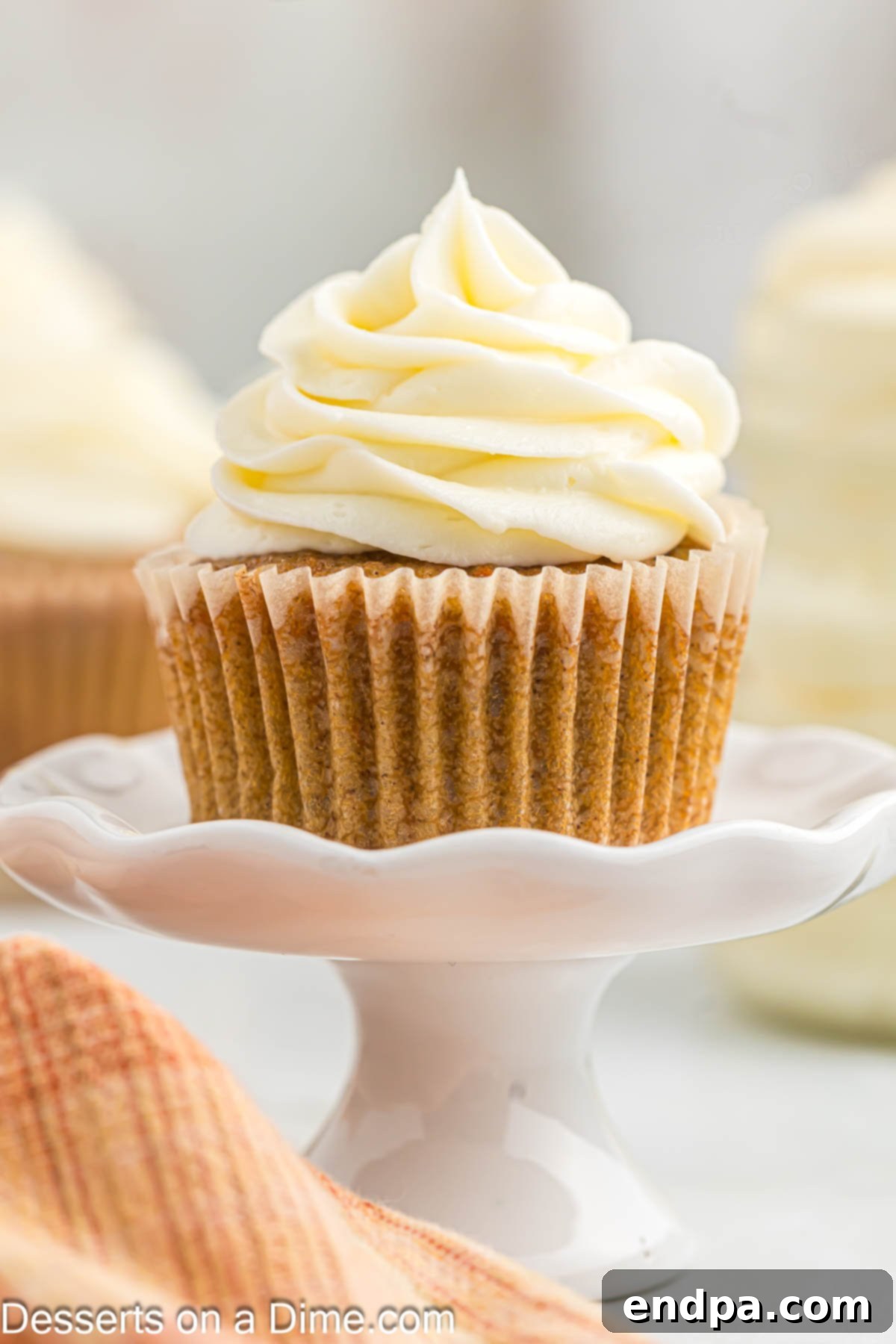 Ultimate Homemade Cream Cheese Frosting 7 Cupcake with frosting on stand.