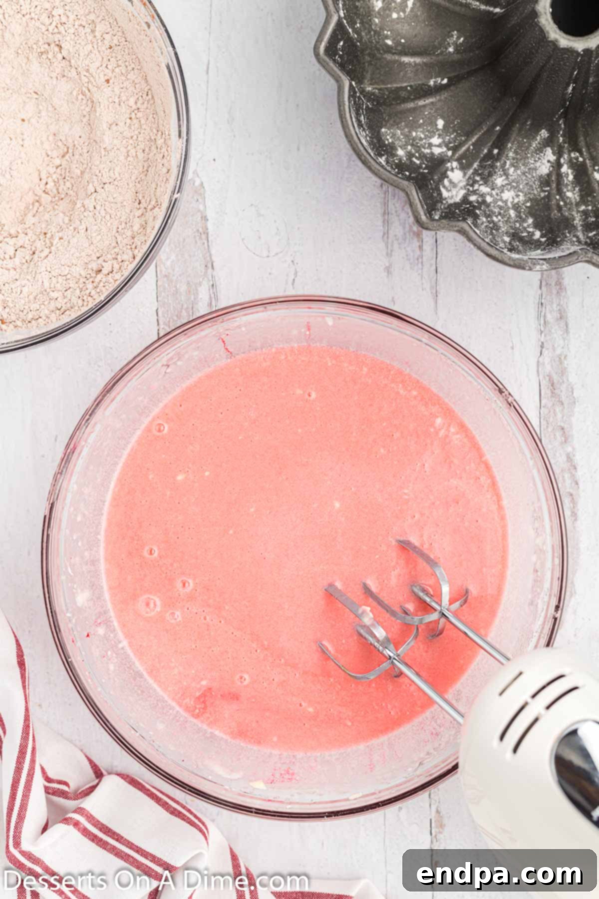 Wet ingredients for Red Velvet Pound Cake, including red food coloring, eggs, and buttermilk, fully mixed into the bowl.