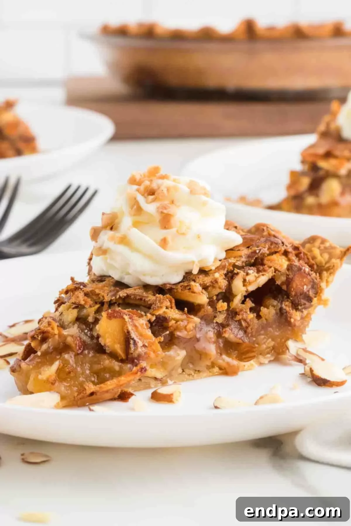 A close-up of a delightful slice of Toffee Almond Pie, adorned with a generous swirl of whipped cream and a delicate sprinkling of almond pieces.
