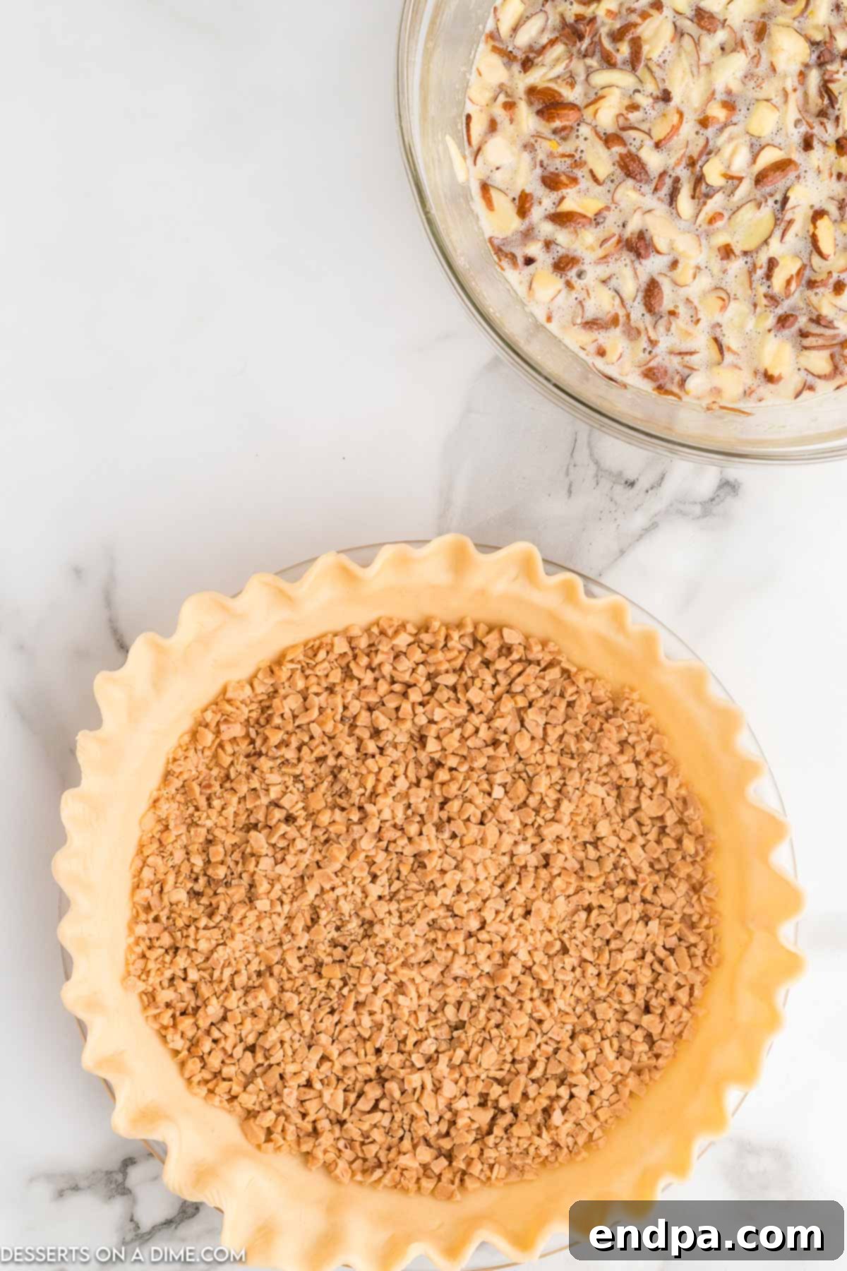 A generous layer of golden toffee crumbs evenly sprinkled across the bottom of the pie crust, ready for the filling.