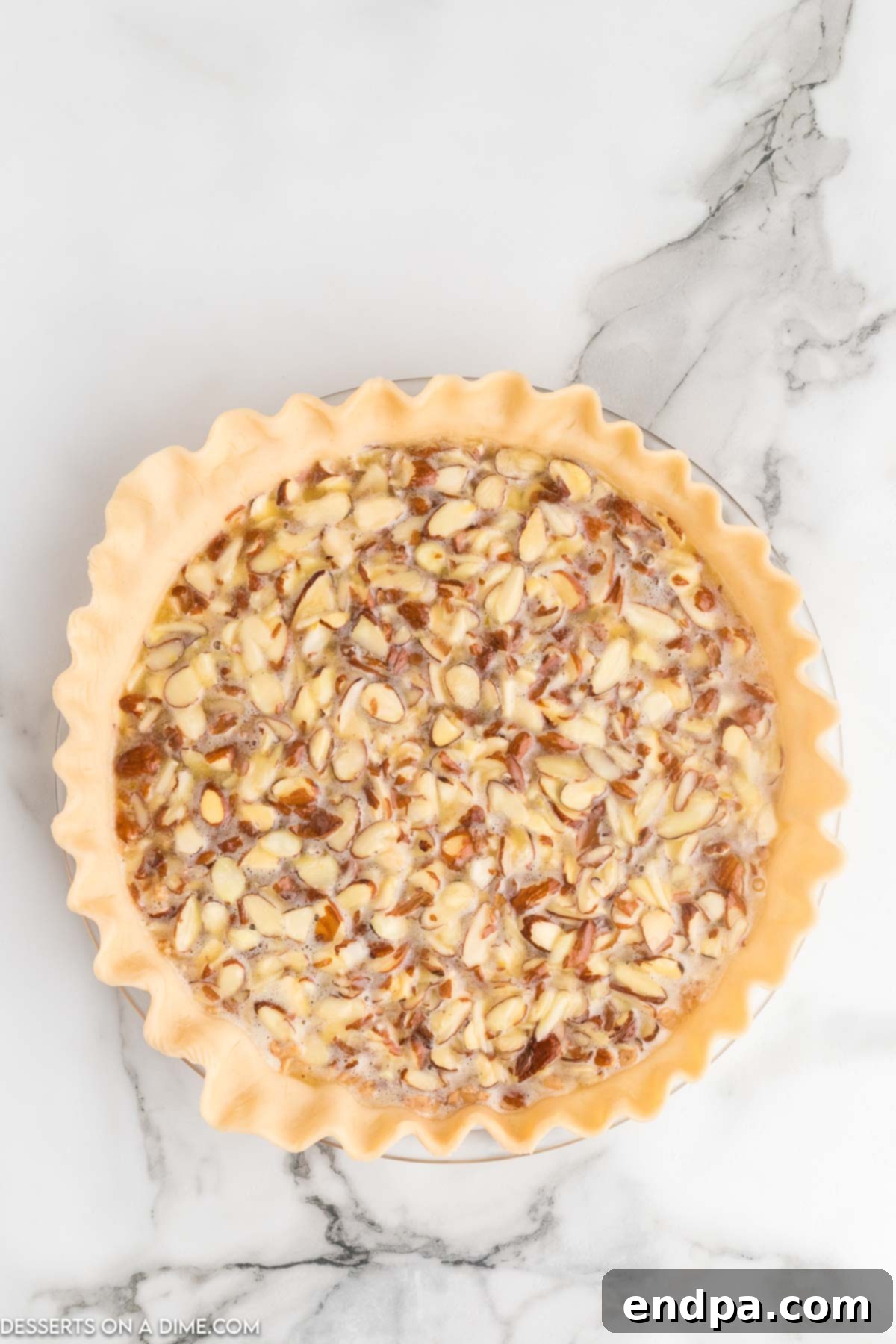 The smooth, nutty pie filling being poured carefully into the prepared pie crust, covering the layer of toffee bits.