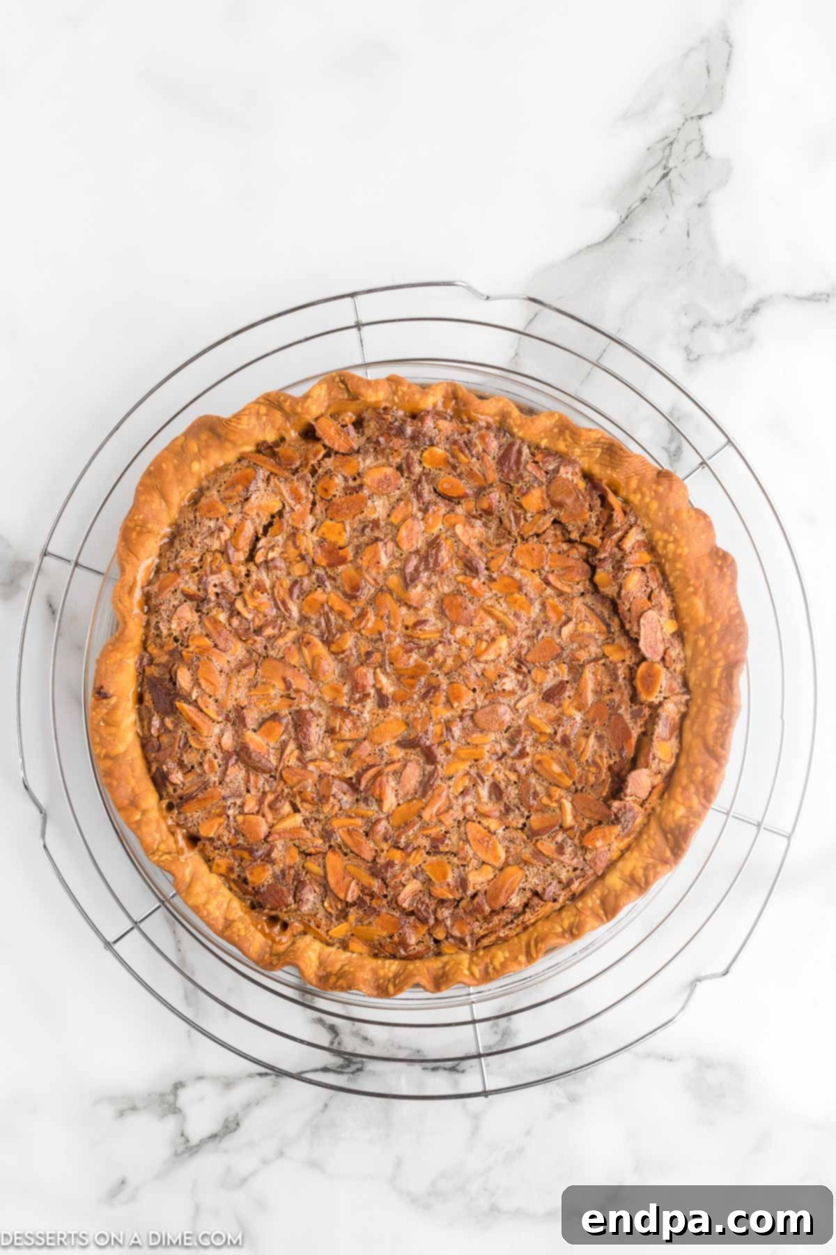 A freshly baked Toffee Almond Pie, golden brown and glistening, cooling on a wire rack after being removed from the oven.