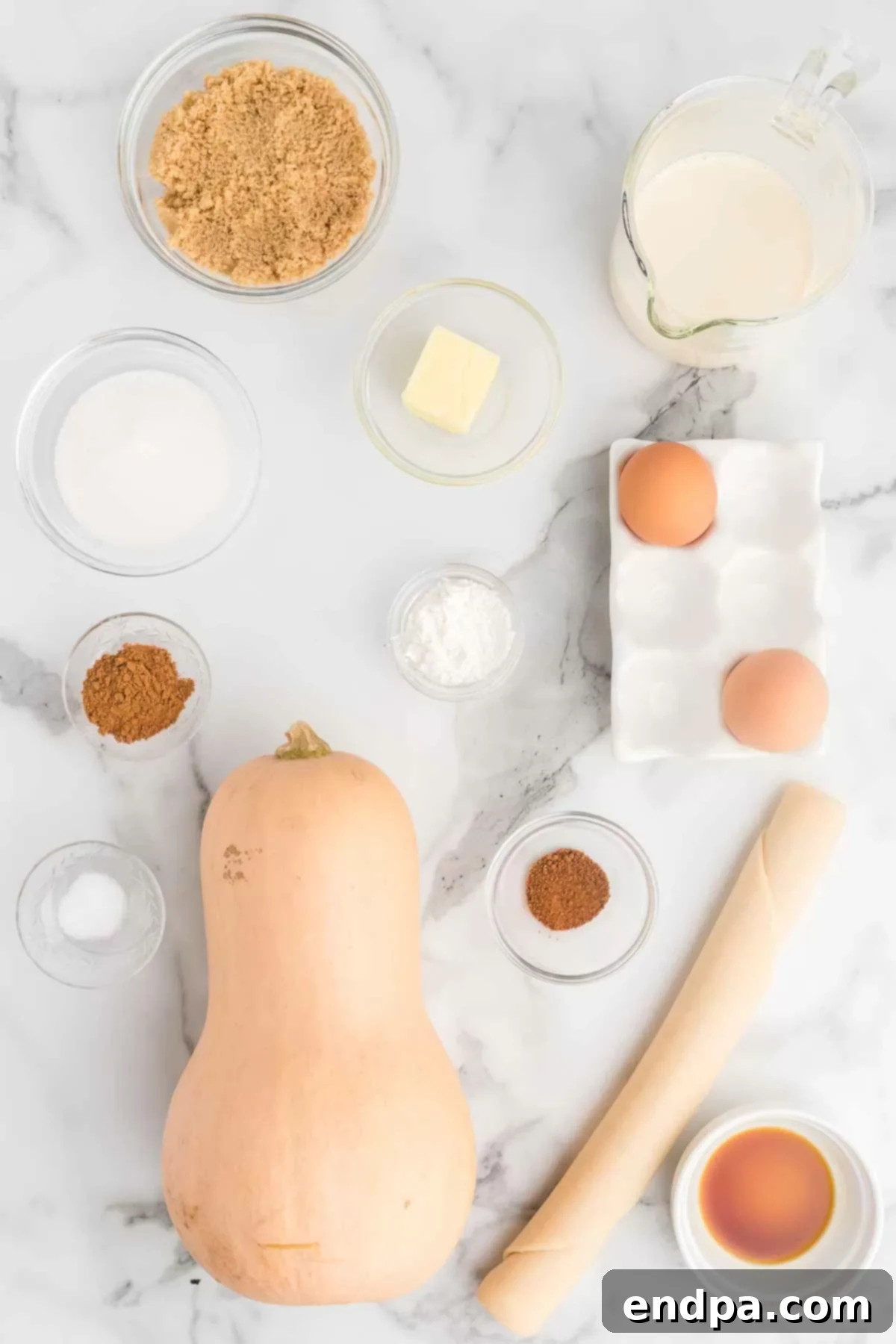 Golden Harvest Butternut Squash Pie 3 Ingredients laid out for Butternut Squash pie: pie crust, butternut squash, butter, brown sugar, white sugar, salt, cornstarch, cinnamon, nutmeg, vanilla extract, eggs, evaporated milk.