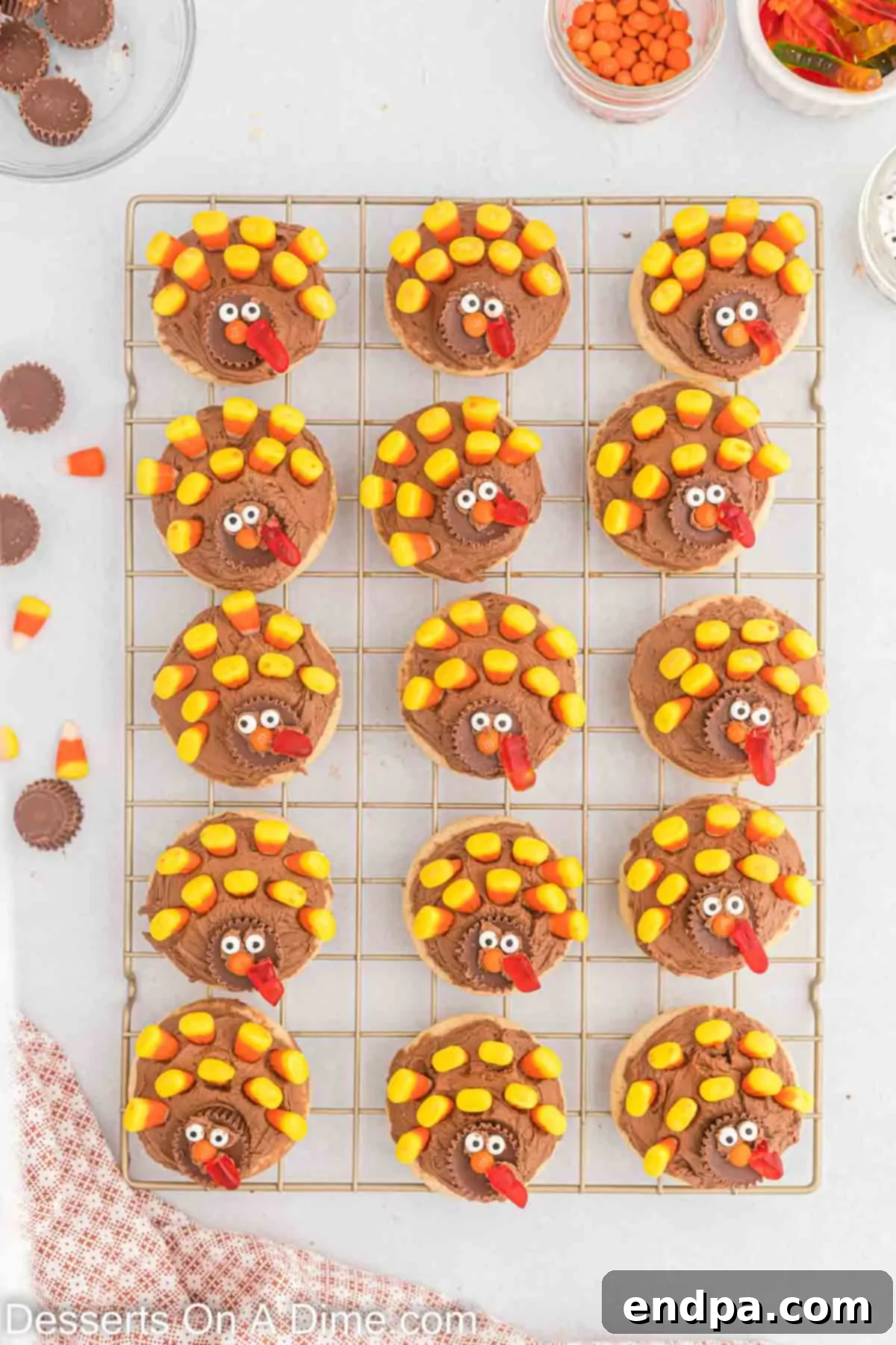Cookies decorated with candy corn feathers, a Reese's cup body, candy eyes, orange M&M beak, and gummy worm wattle to resemble turkeys.