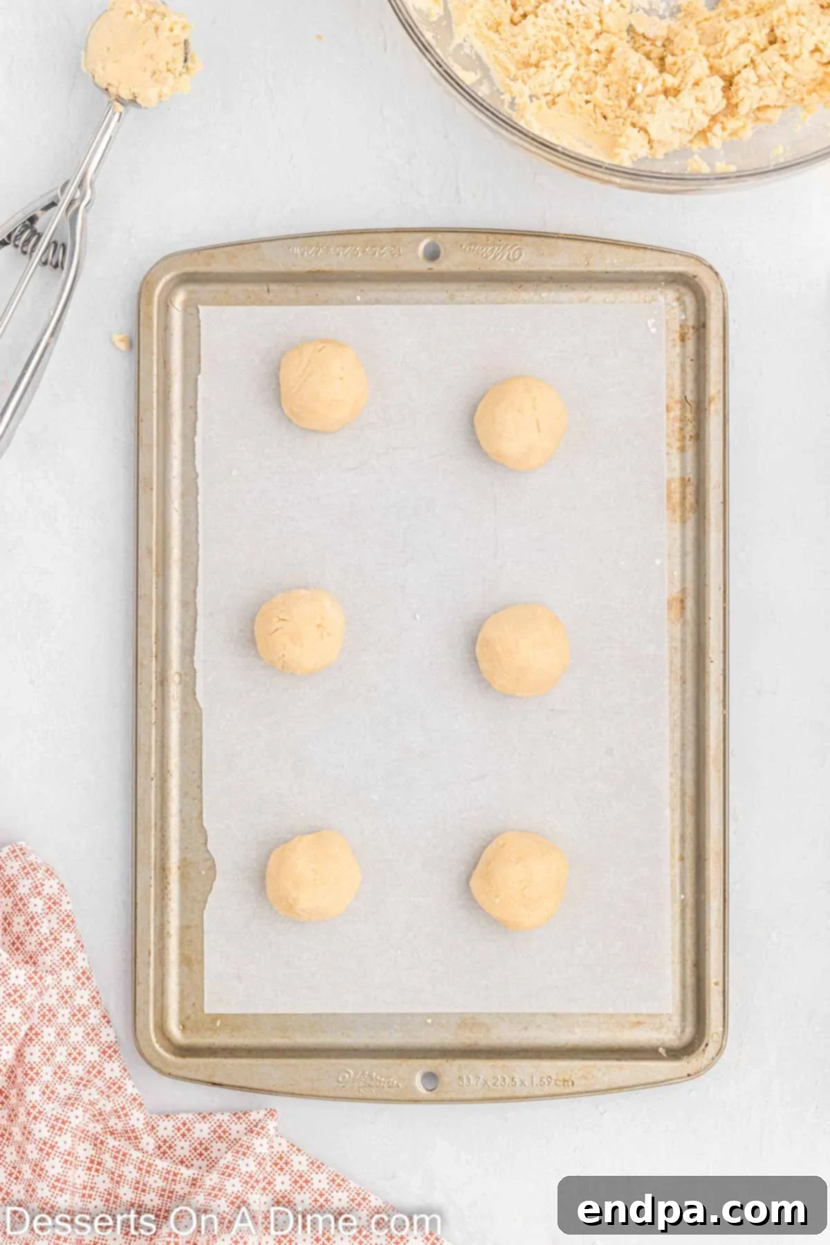 Cookie dough scooped into balls and placed on baking sheets, spaced apart.