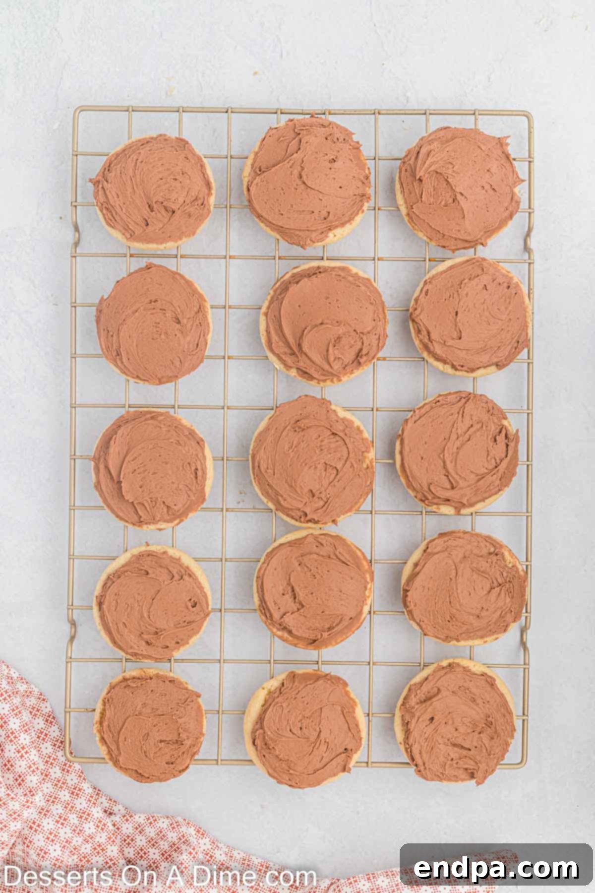 Cooled cookies being frosted with chocolate buttercream.