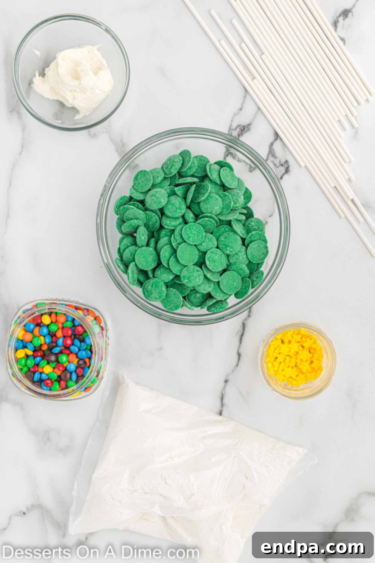 Ingredients needed for Christmas Tree Cake Pops: vanilla cake mix, vanilla frosting, green candy melts, mini M&Ms, yellow star sprinkles, lollipop sticks.