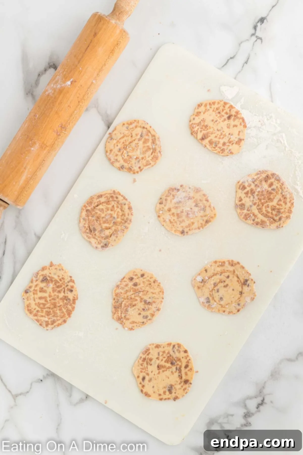 Cinnamon rolls unrolled and lightly floured on a cutting board, ready for rolling.