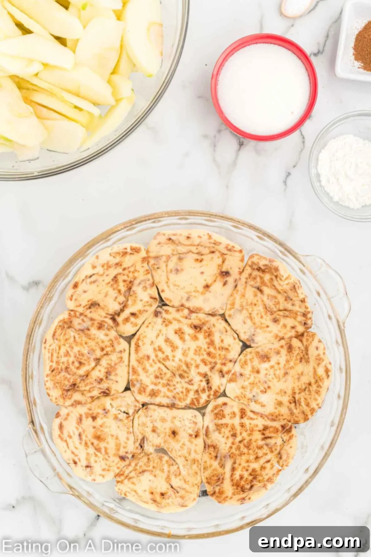 Flattened cinnamon roll pieces pressed into the bottom of a pie plate, forming the pie crust.