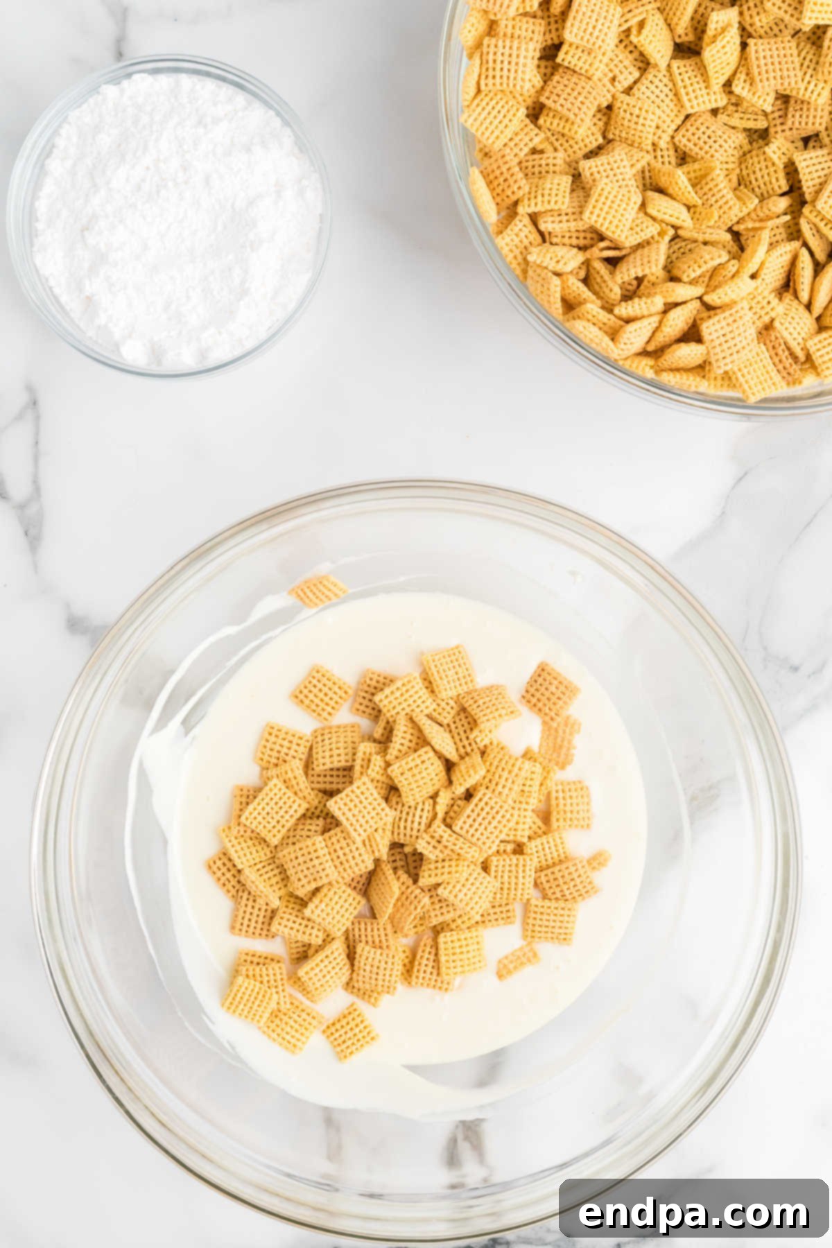 Cream cheese frosting melted in a bowl, with Chex cereal gently being folded in to coat.
